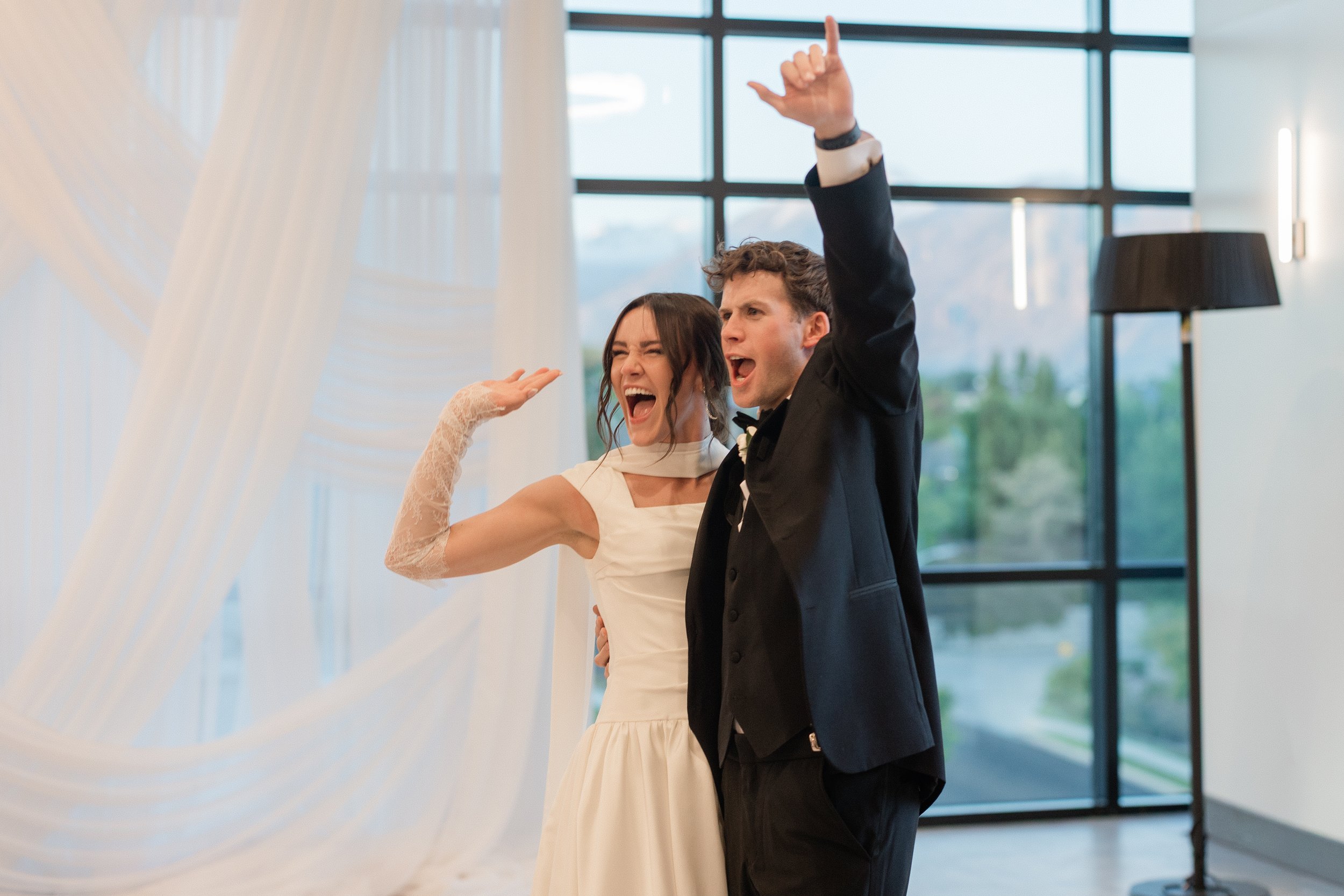 Bride and groom stand hugging each other and waving to guests.