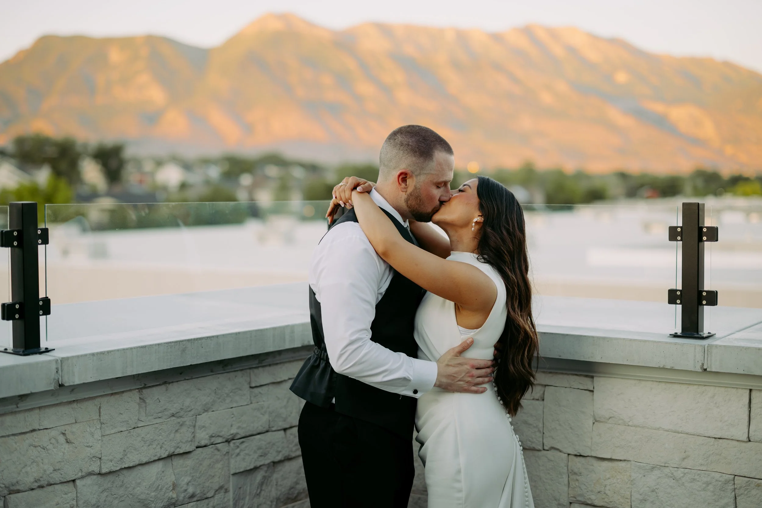 Bride and groom hug while kissing in the courtyard with the mountains in the background.