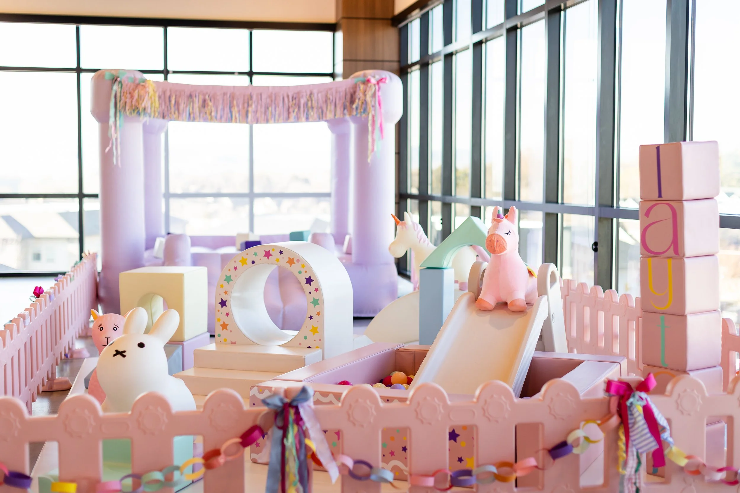 Toddler-friendly soft play setup with miniature bounce house and a small slide into a ball pit.