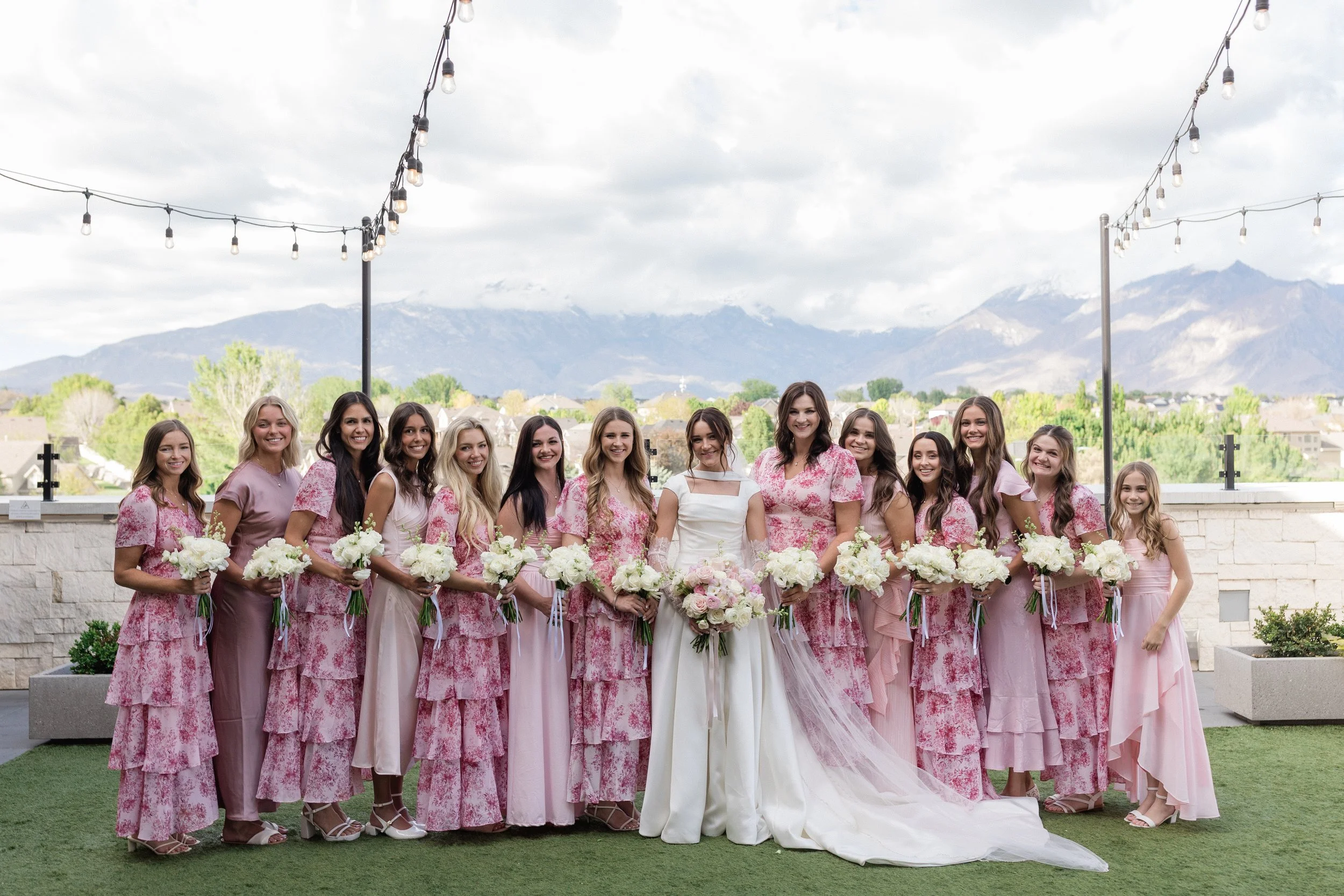 Bride and bridesmaids line up across the courtyard and smile for the camera.