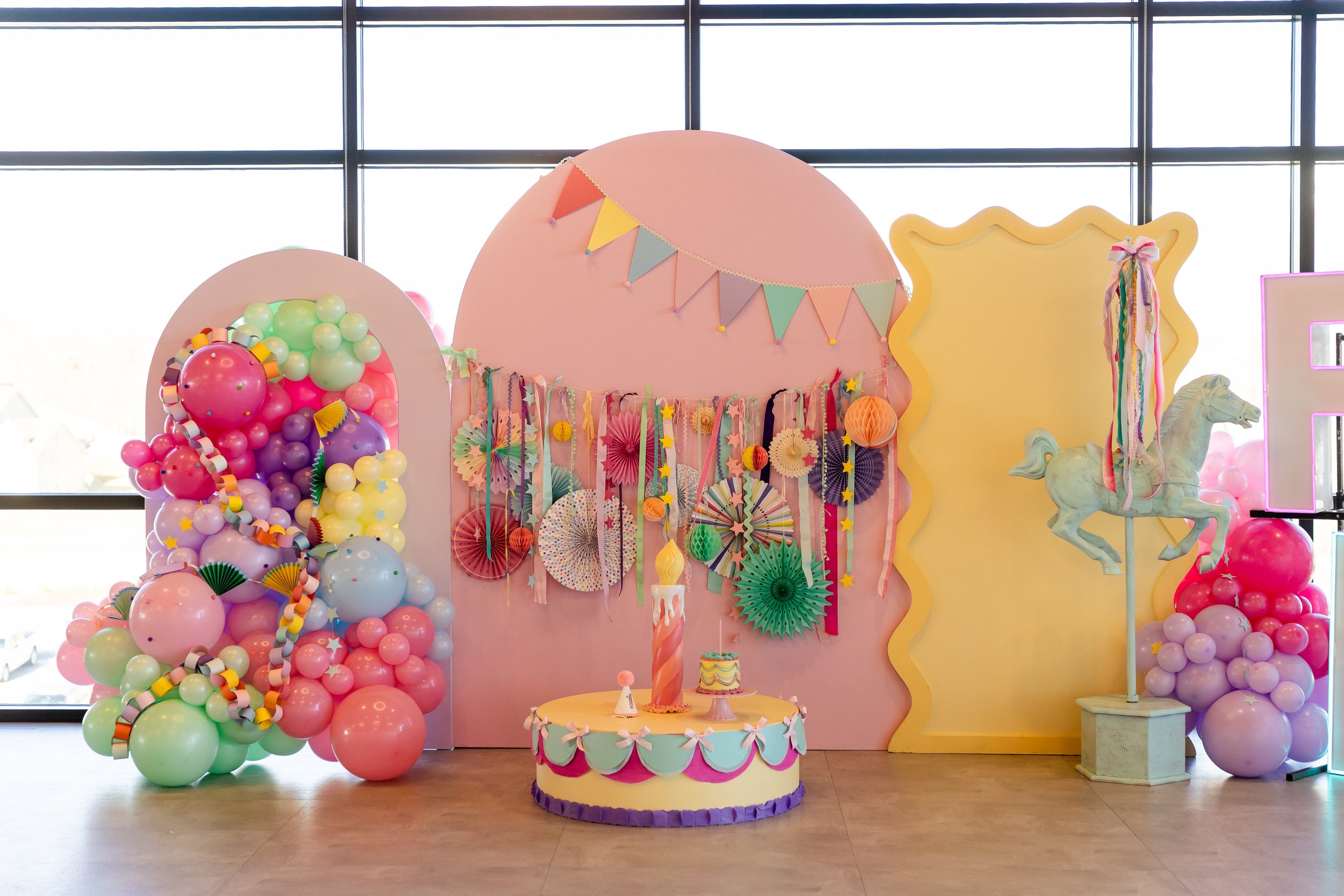 Pink, yellow, purple, and green party decoration setup.