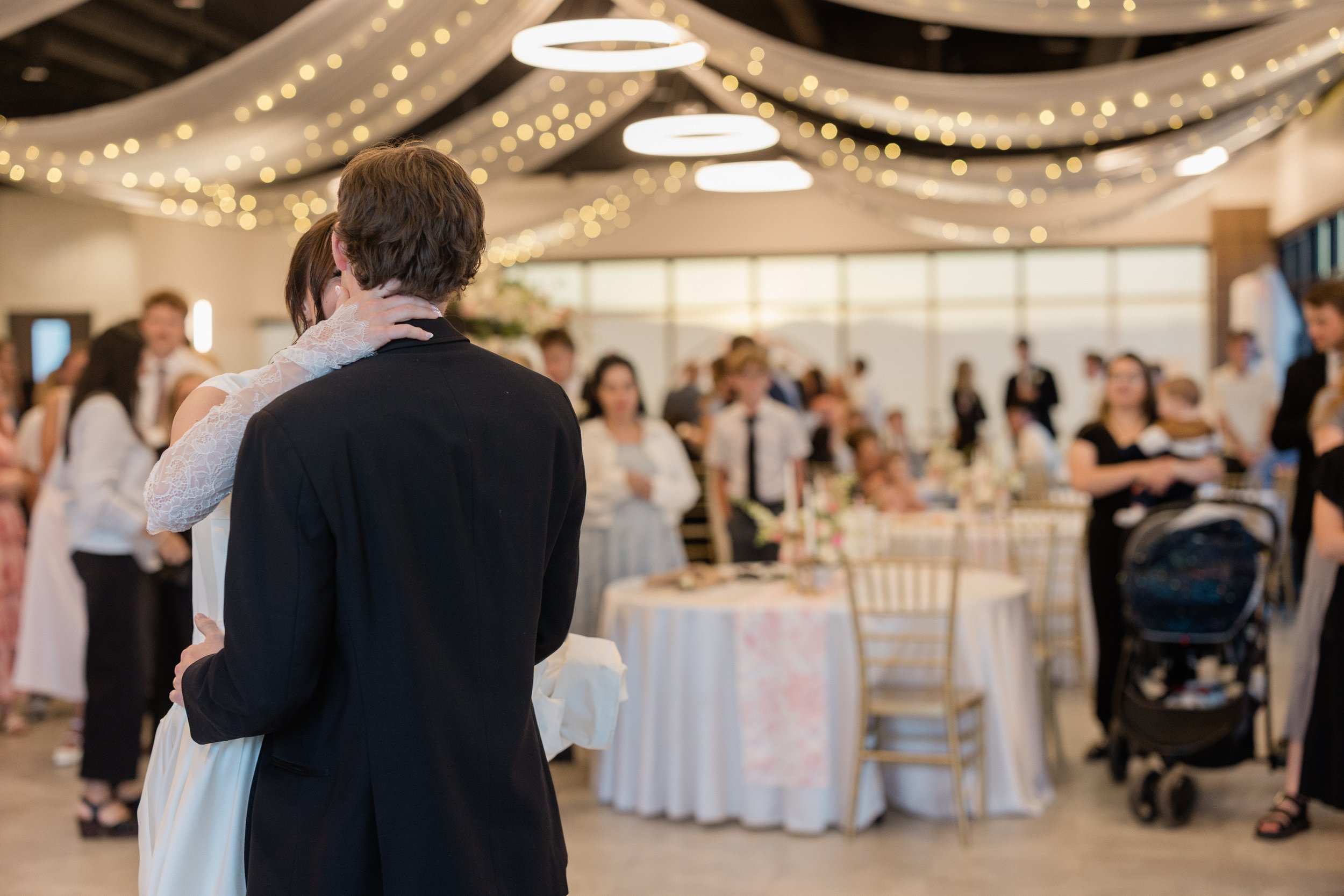 Bride and groom slow dance in front of wedding guests.