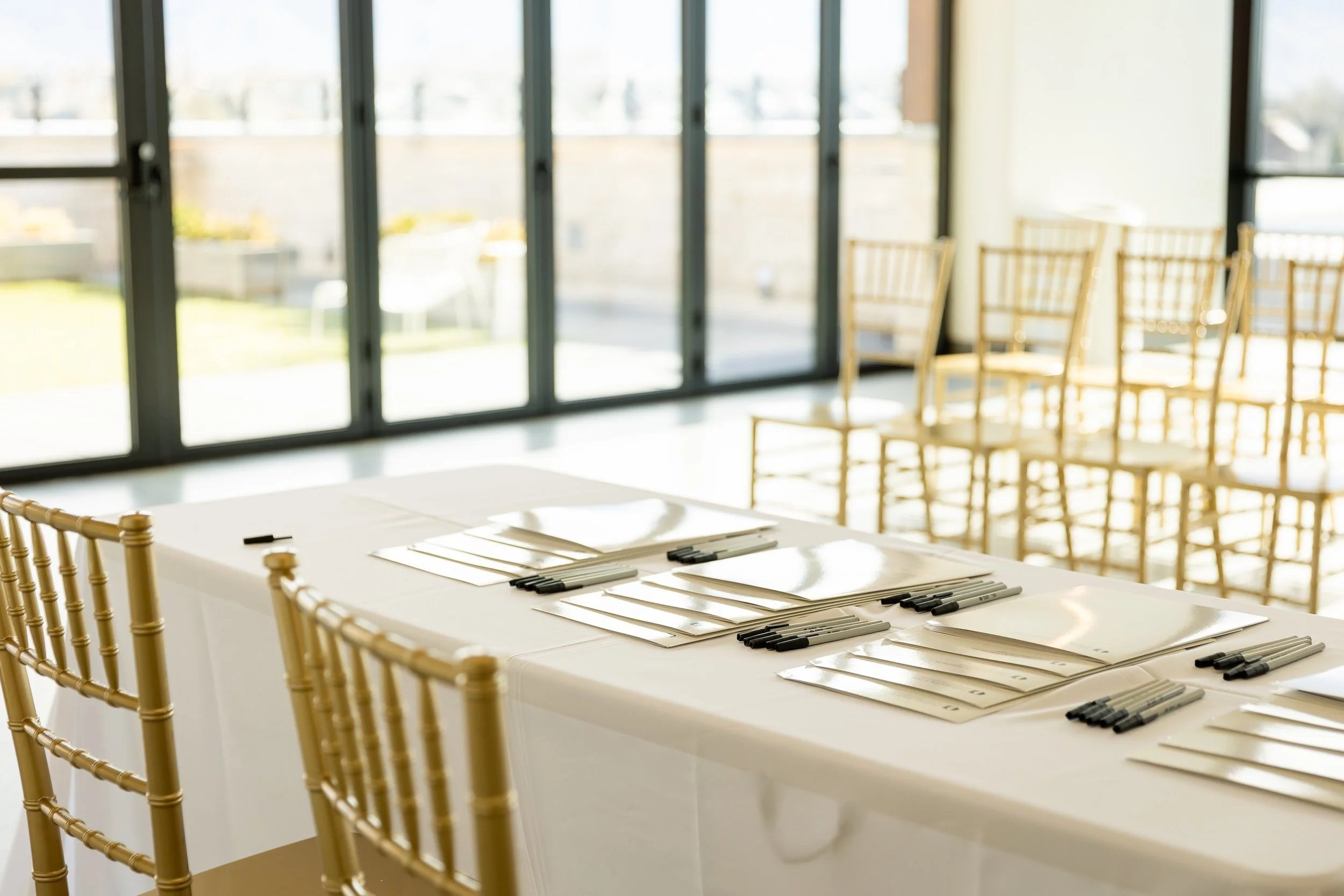 White rectangle table set up with white tablecloth and tablets and pens on the table.