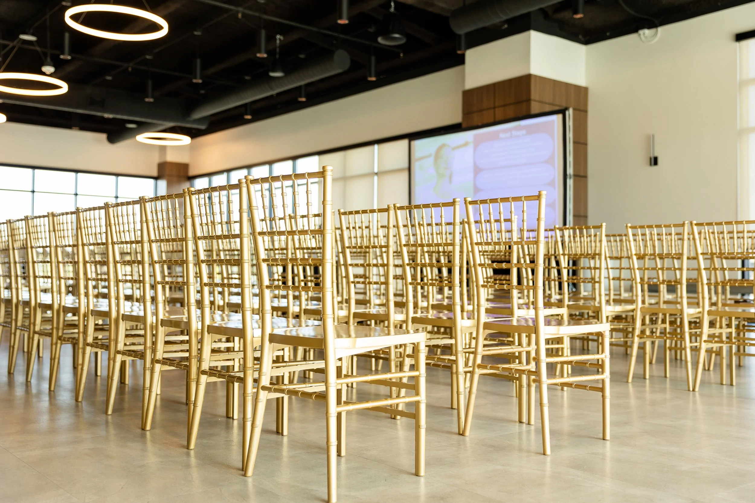 Rows of gold chairs setup for a business presentation.