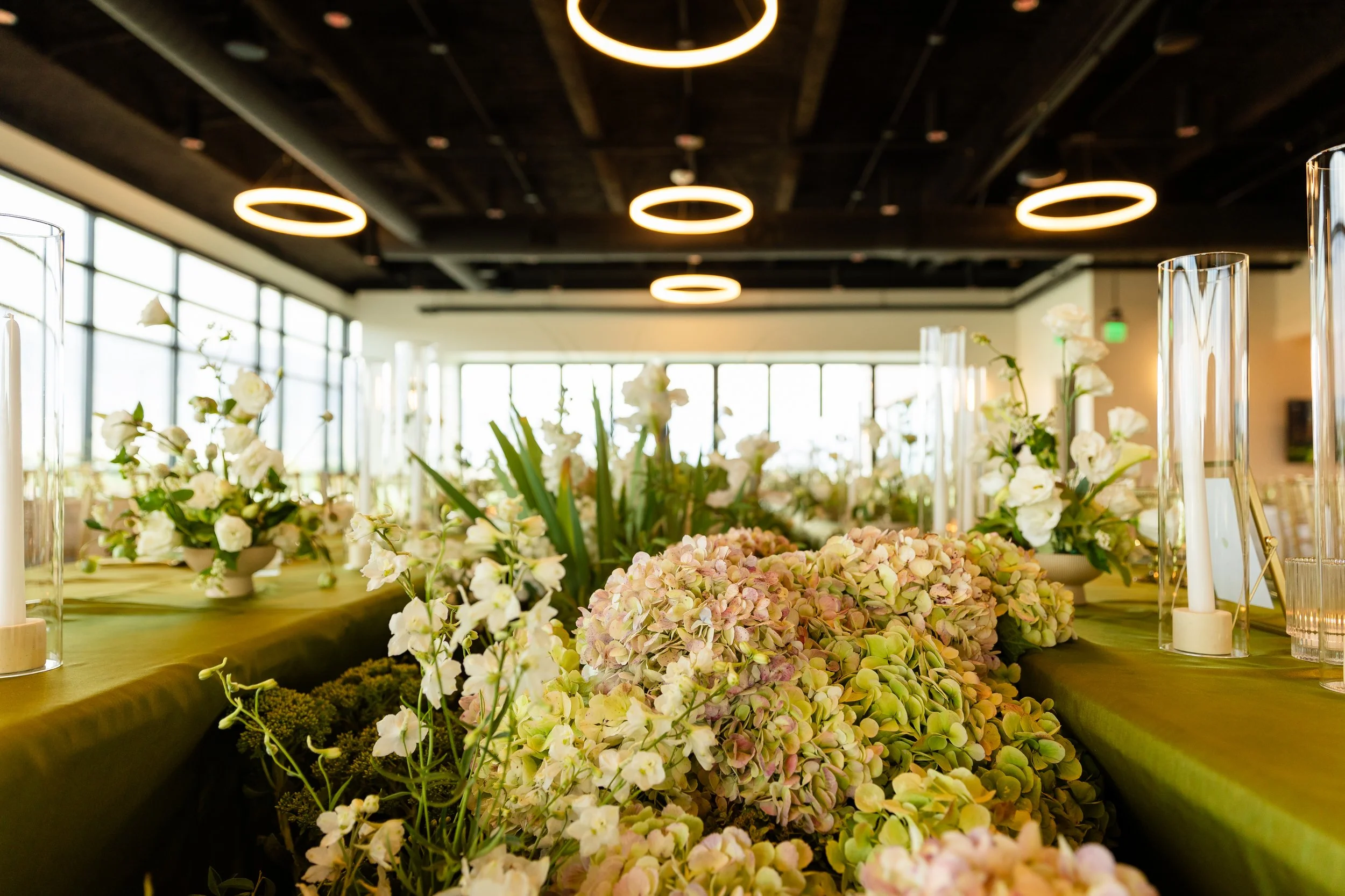 A floral meadow between two long tables that are covered in citron-colored linens.