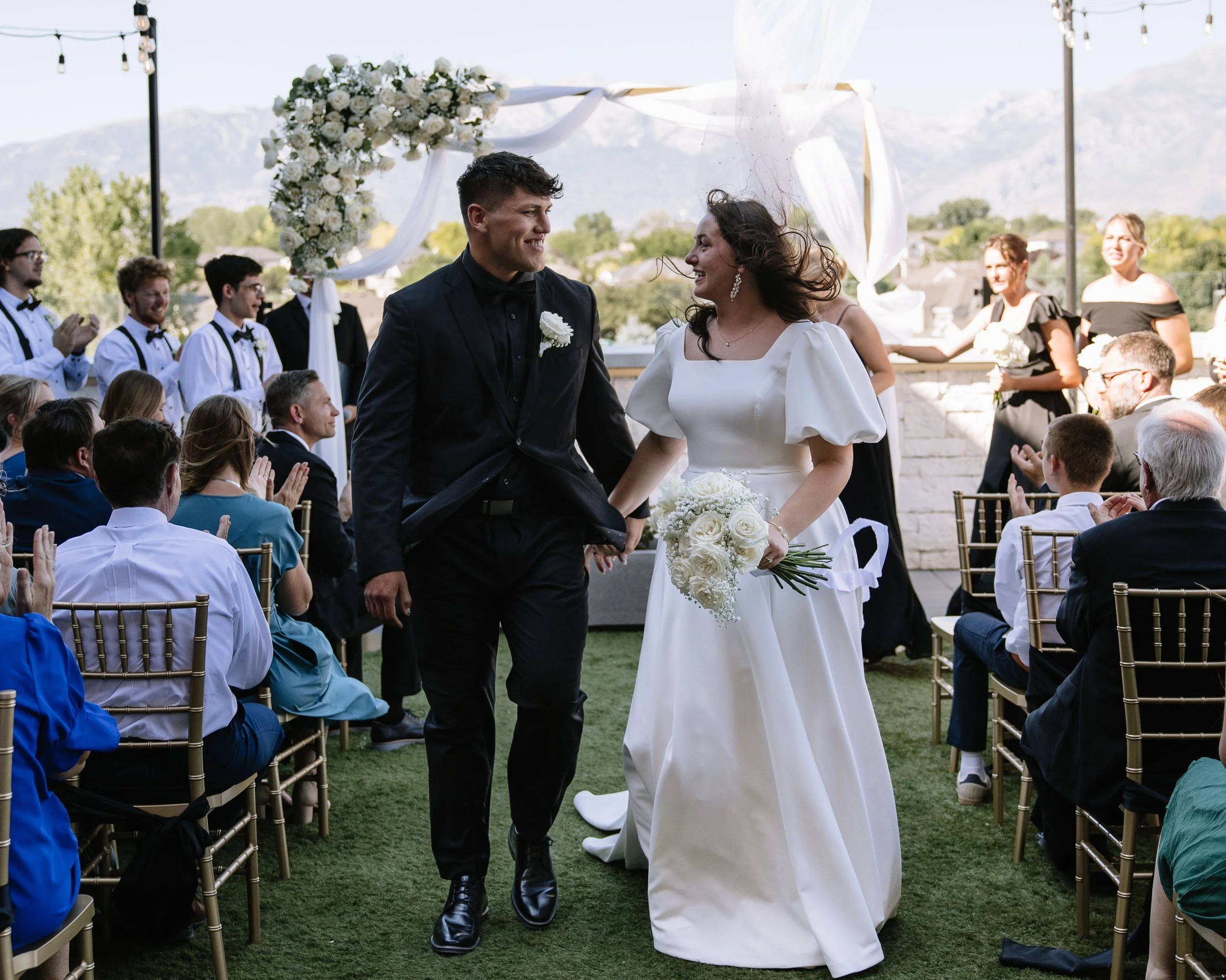 The bride and groom walk down the aisle in the courtyard.