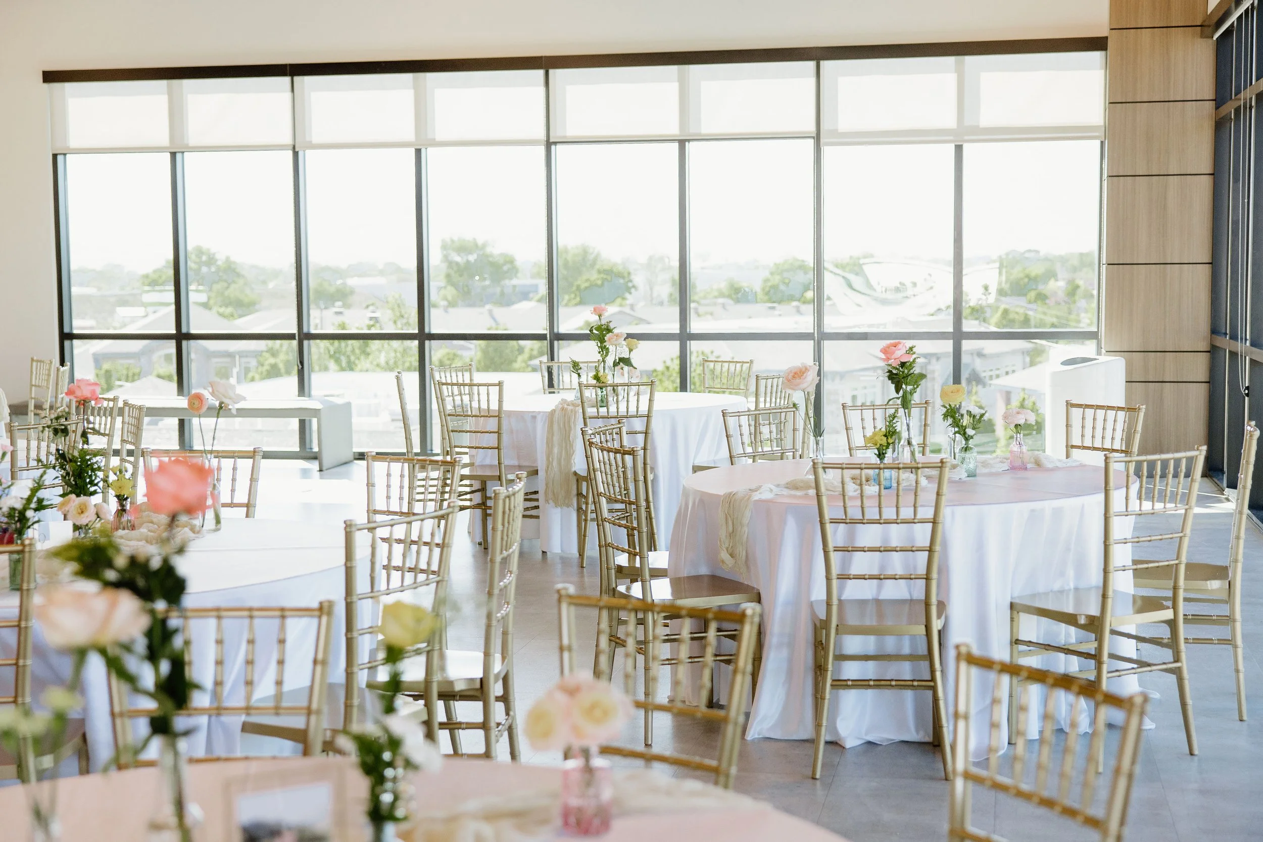 Round tables setup with white linens, and spring colored florals.
