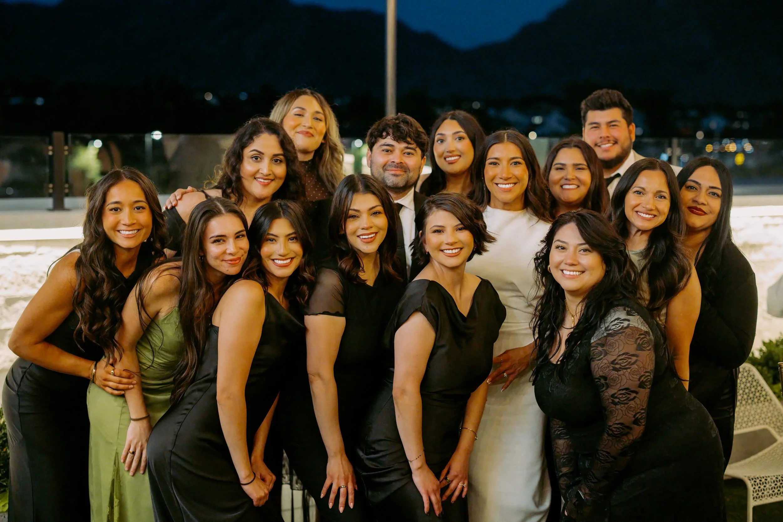 Men and women dressed in formal clothing stand near each other smiling at the camera in the courtyard.