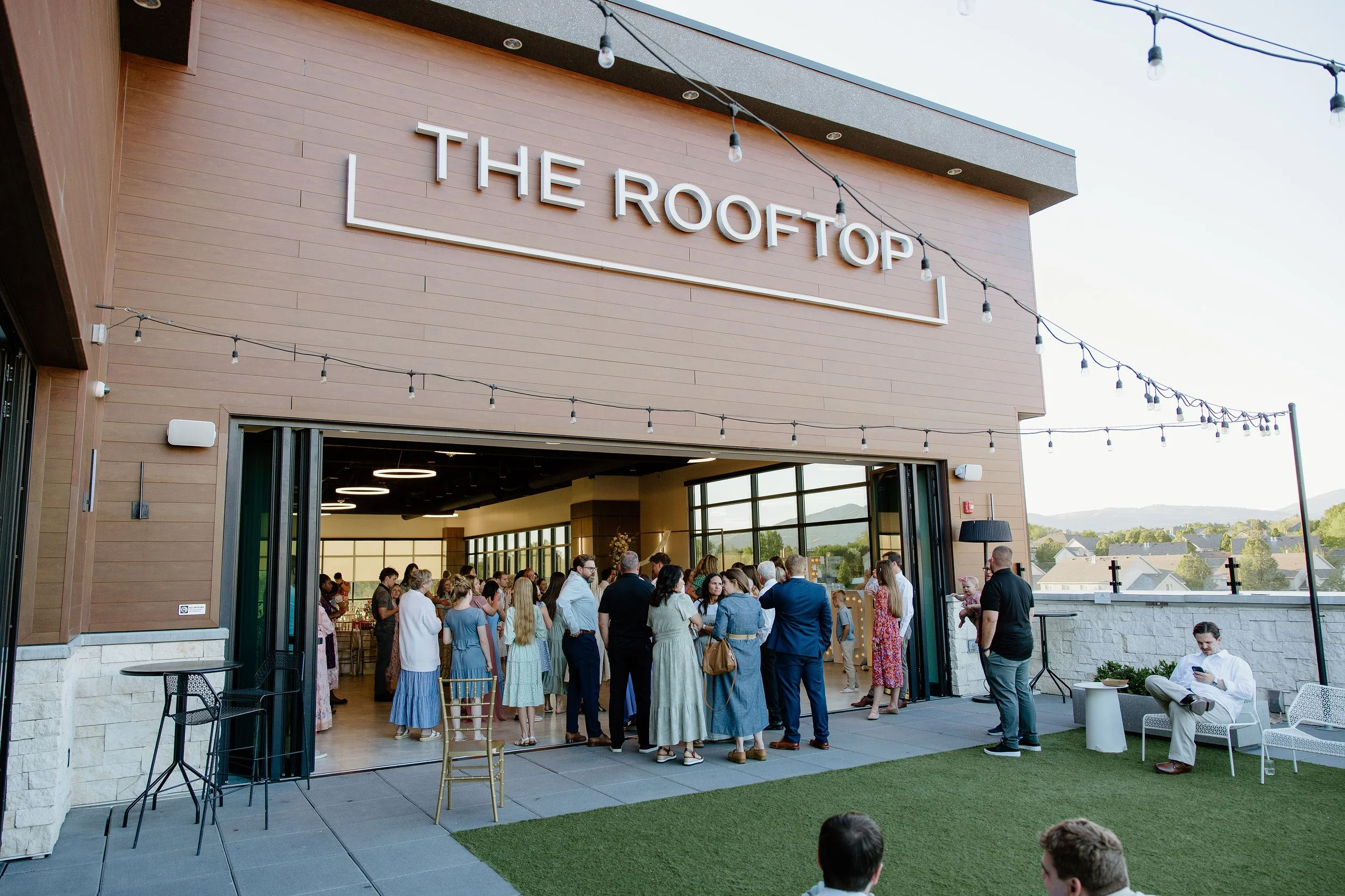 Wedding guests gathering in the courtyard under bistro lights.