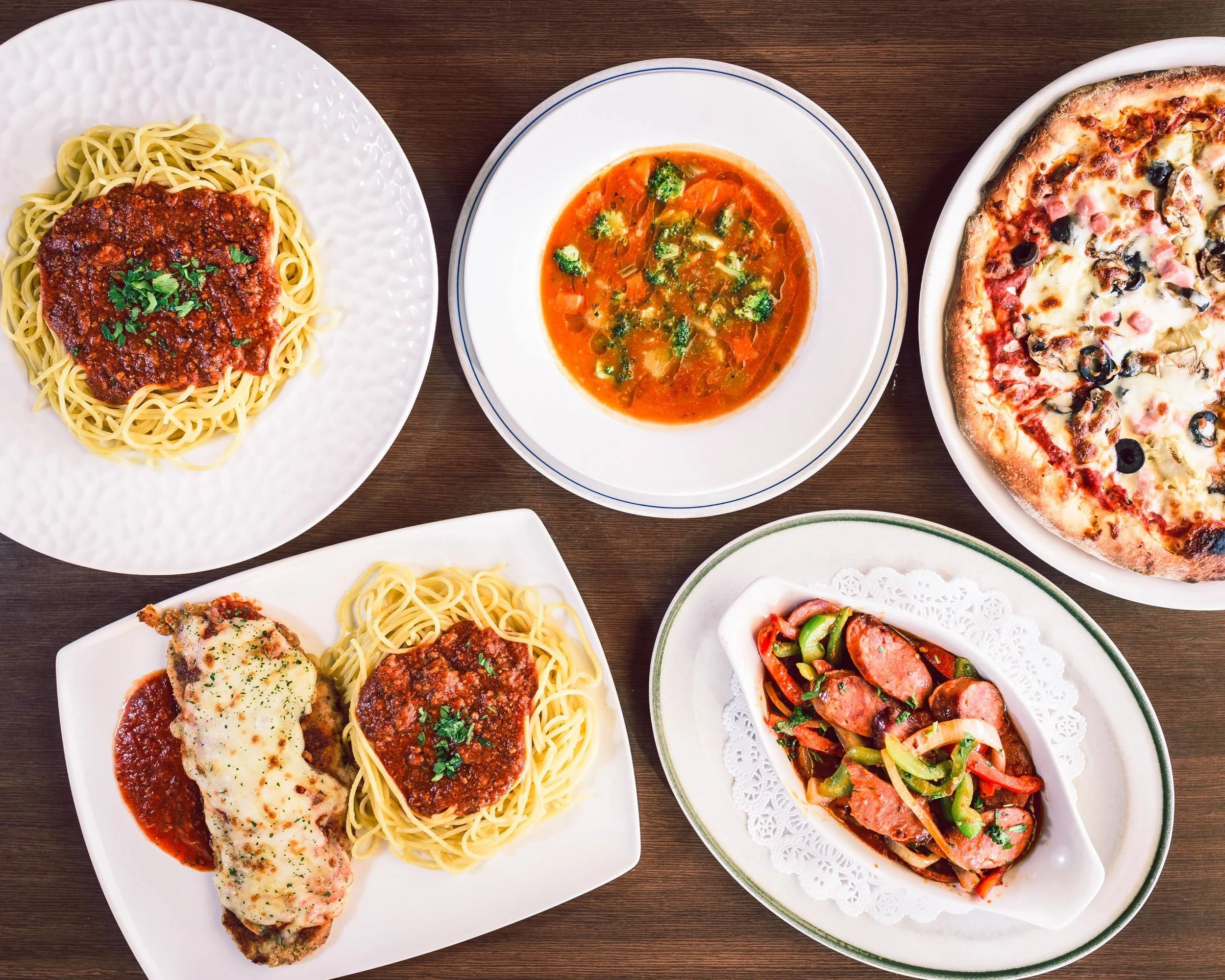 Pasta, soup, pizza and chicken parmesan displayed on 5 white plates