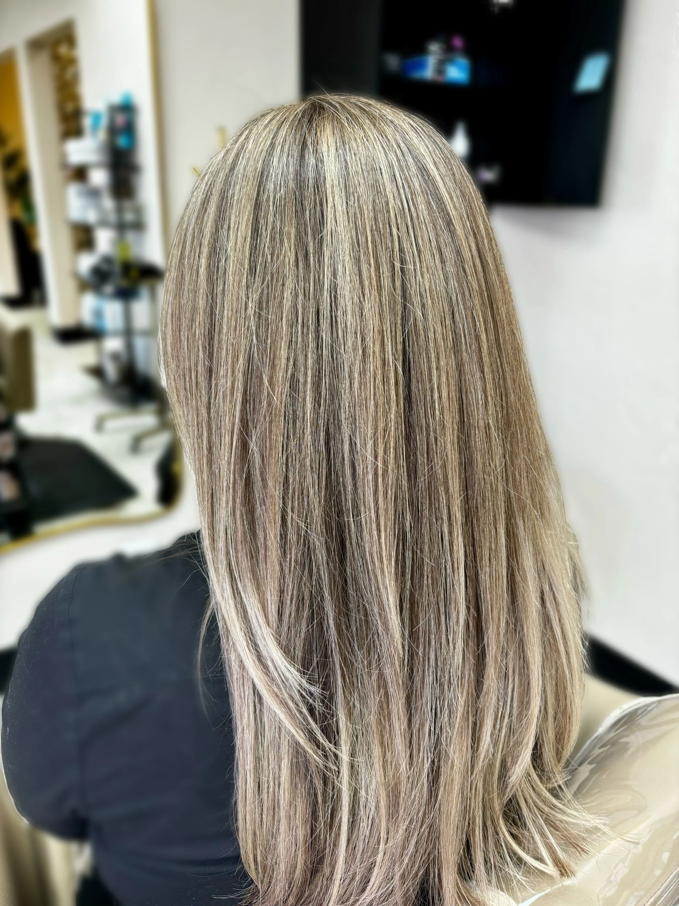 Close-up of woman with highlighted blonde hair in a salon setting.