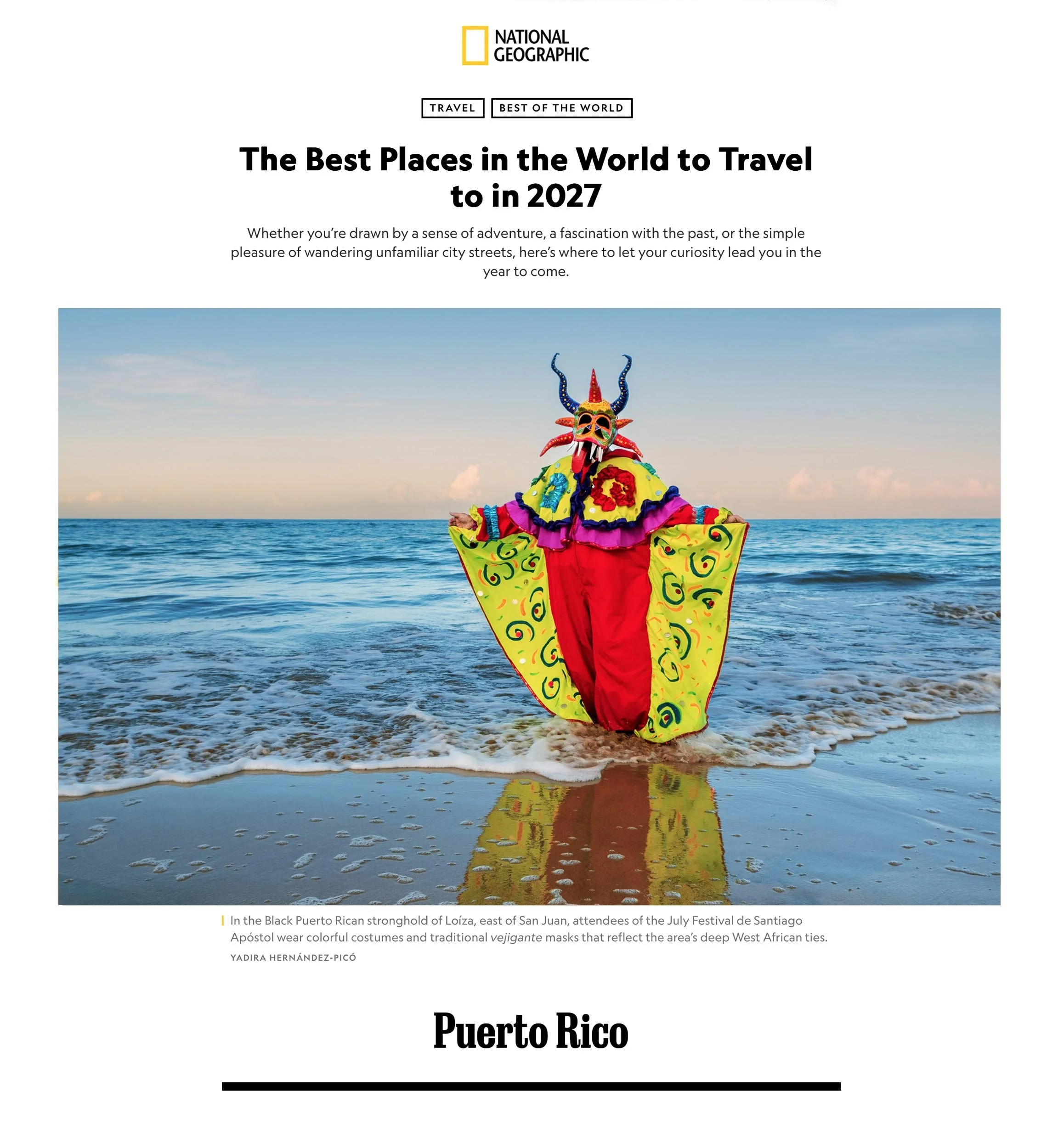 Traditional Puerto Rican vejigante mask and vibrant costume standing in the ocean at Loíza beach, photographed by Yadira Hernández-Picó for National Geographic.