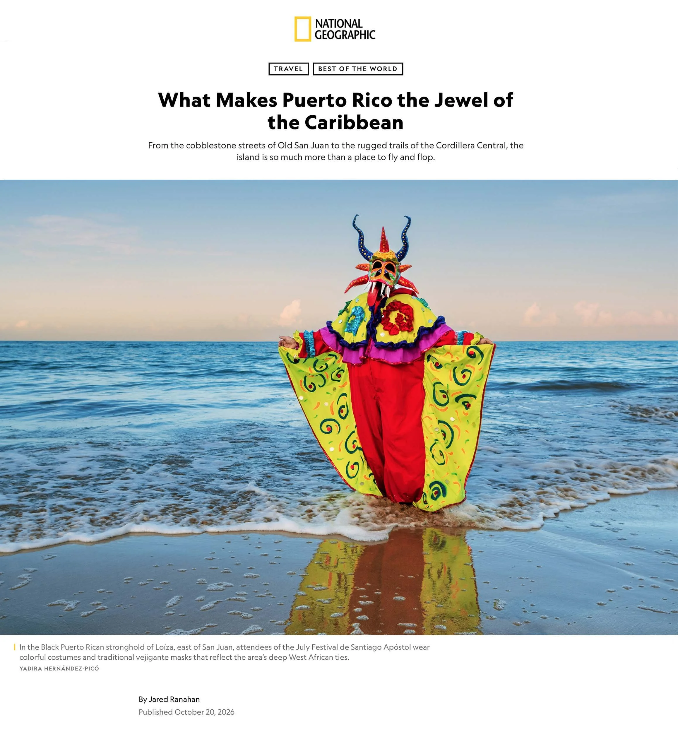 Traditional Puerto Rican vejigante mask and vibrant costume standing in the ocean at Loíza beach, photographed by Yadira Hernández-Picó for National Geographic.