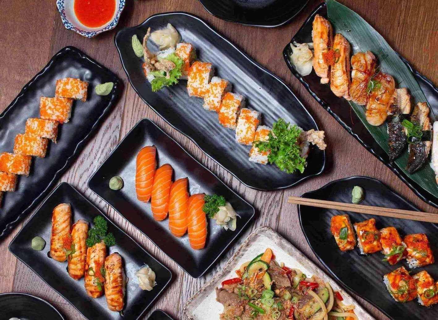 black plates of nigiri and sushi rolls