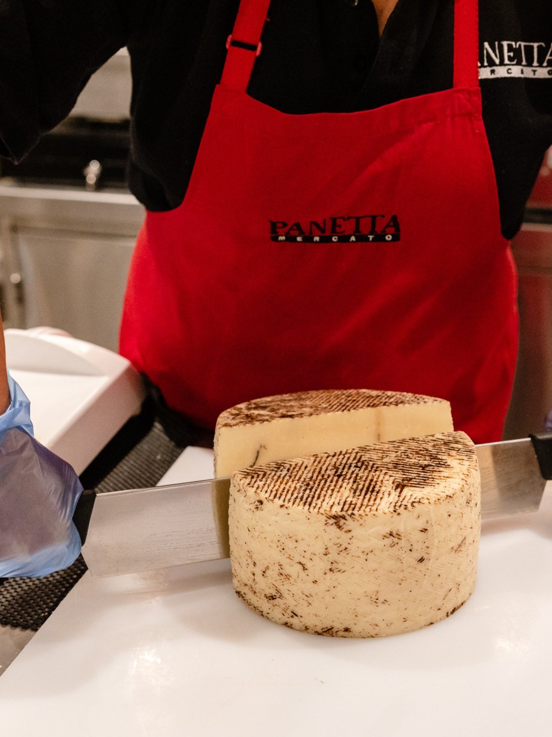 Staff member slicing cheese at the Panetta Mercato deli counter, Kirrawee