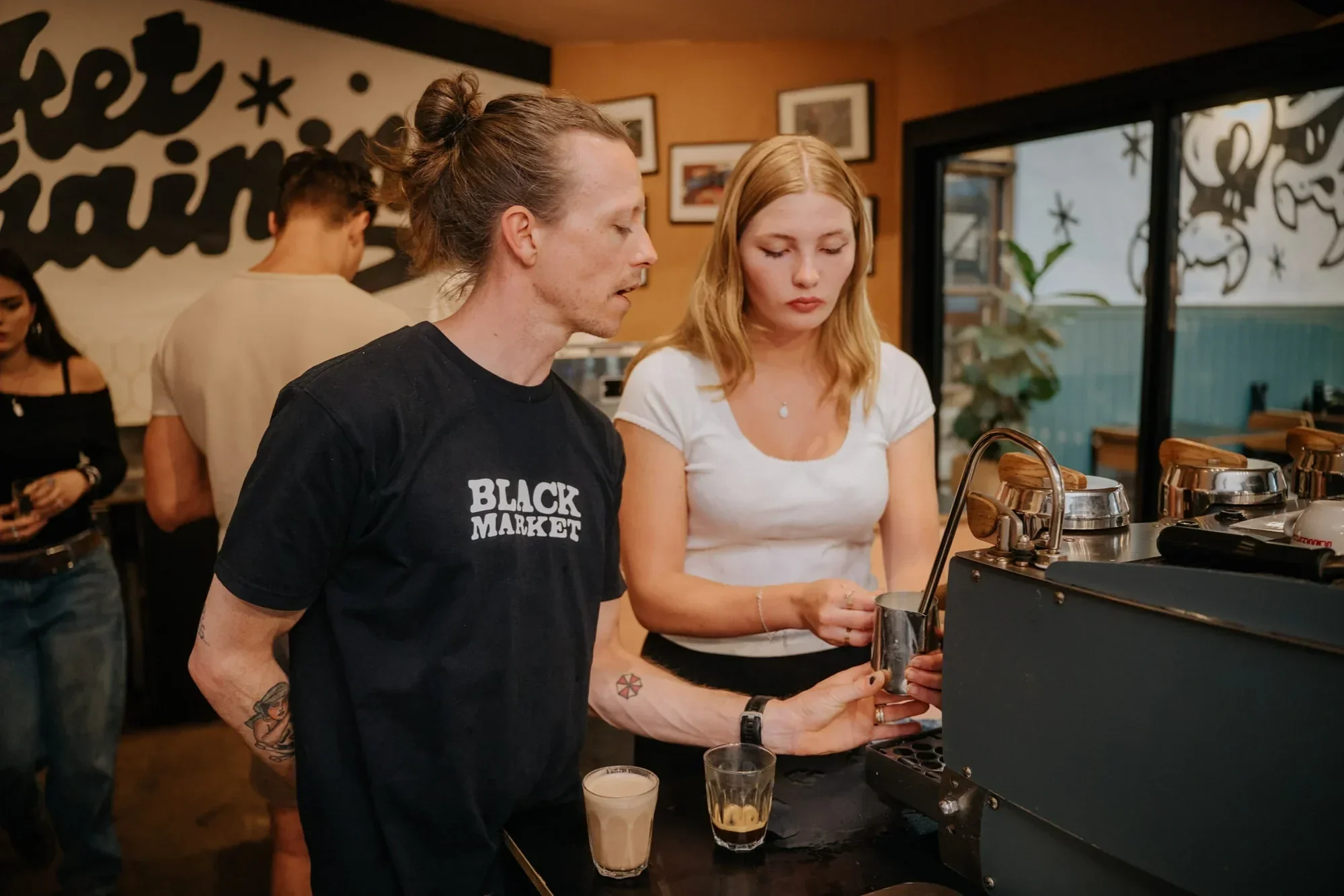 Black Market Coffee barista training session, staff learning to steam milk at the espresso machine