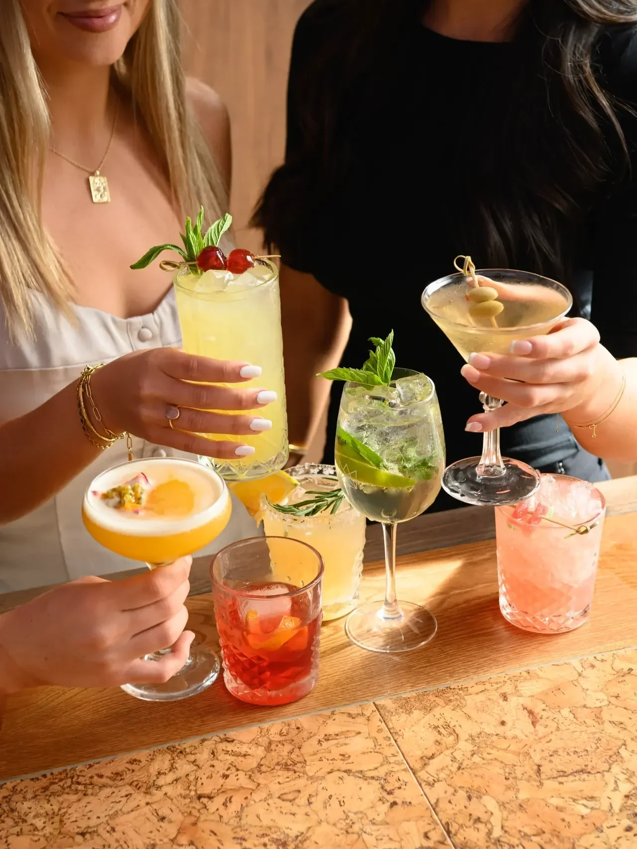 Guests enjoying a colourful selection of cocktails at The Prince Hotel, featuring refreshing spritzes, martinis and citrus-garnished drinks gathered around a timber bar table.