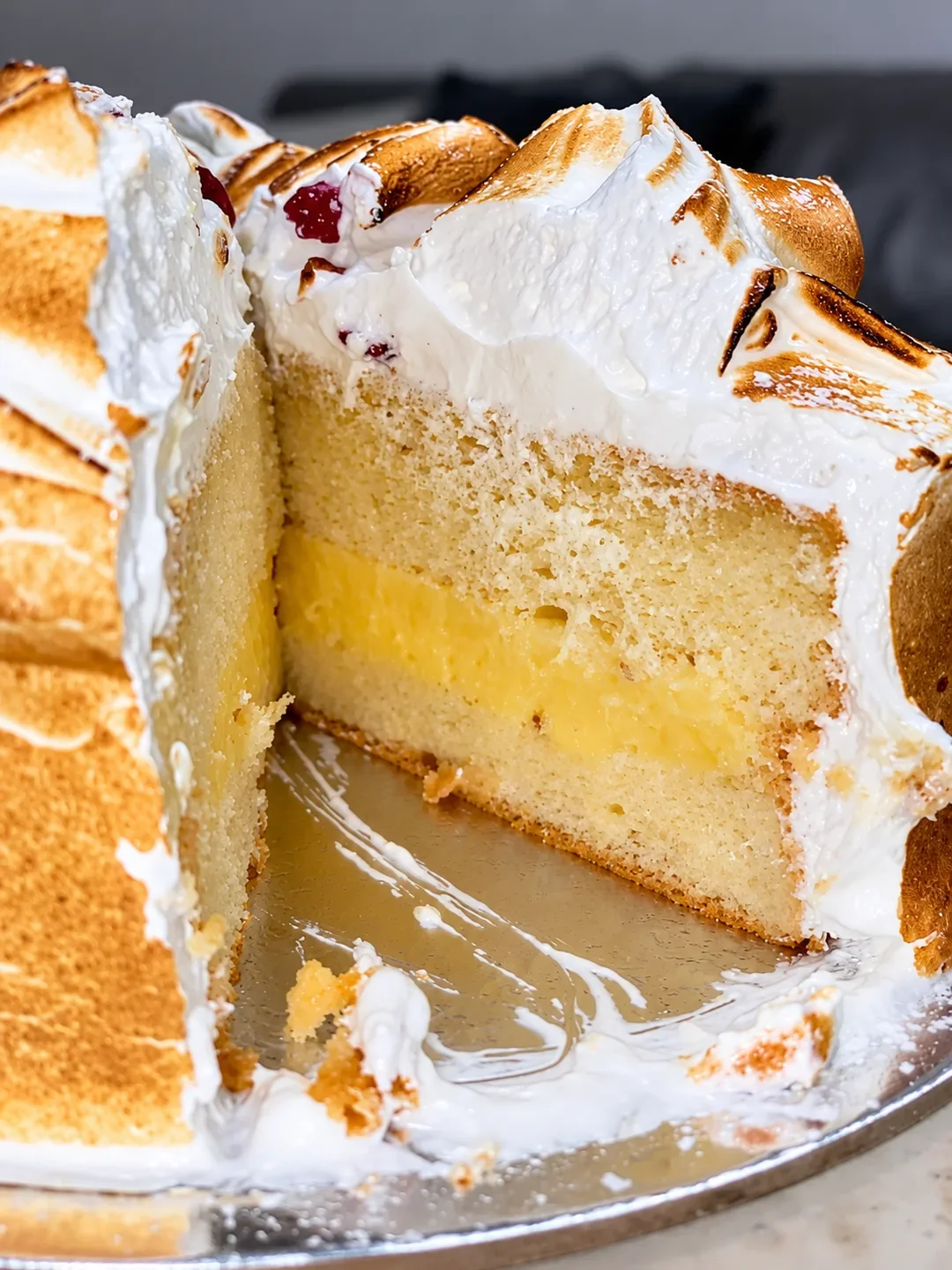 A sliced cake with sponge layers, a yellow filling and toasted meringue at Sweet Mayhem in Sutherland.