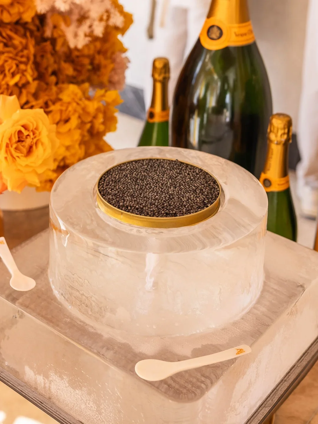 Luxury caviar presentation at Bobby’s in Cronulla, featuring a generous serving of black caviar displayed on a sculptural ice stand, surrounded by Perrier-Jouët Champagne bottles and vibrant yellow floral arrangements.