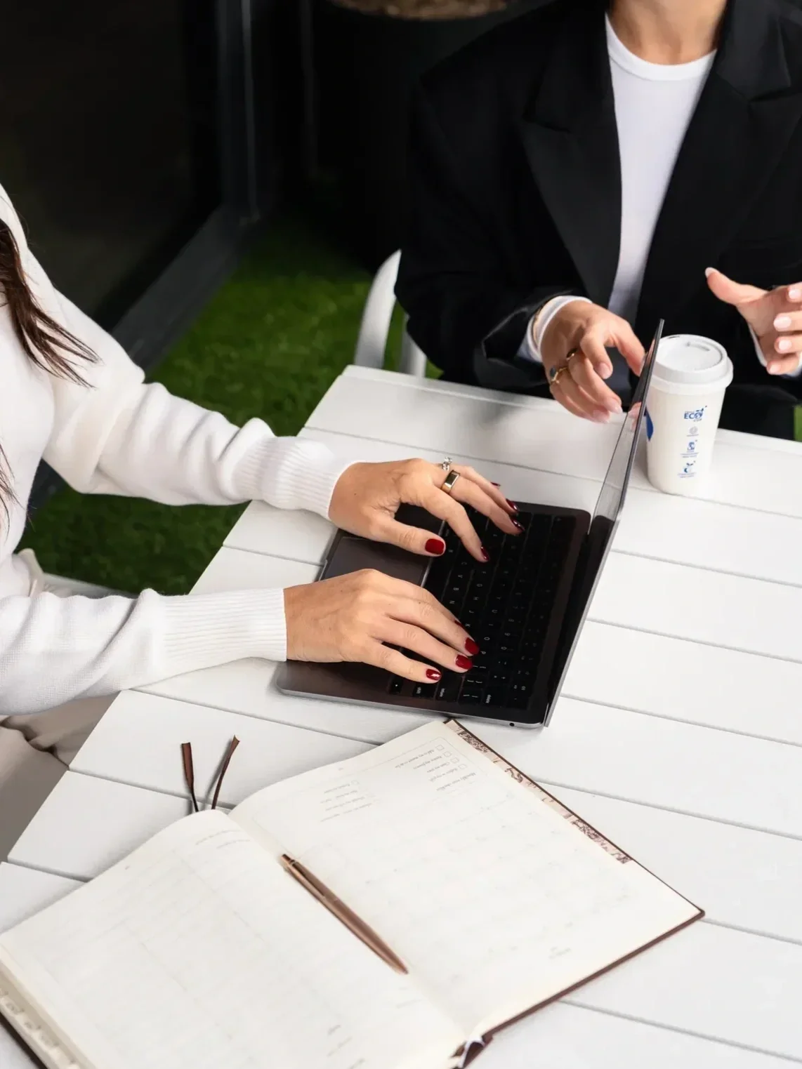 Female mortgage broker speaking with a client, with a laptop and diary visible on the table.