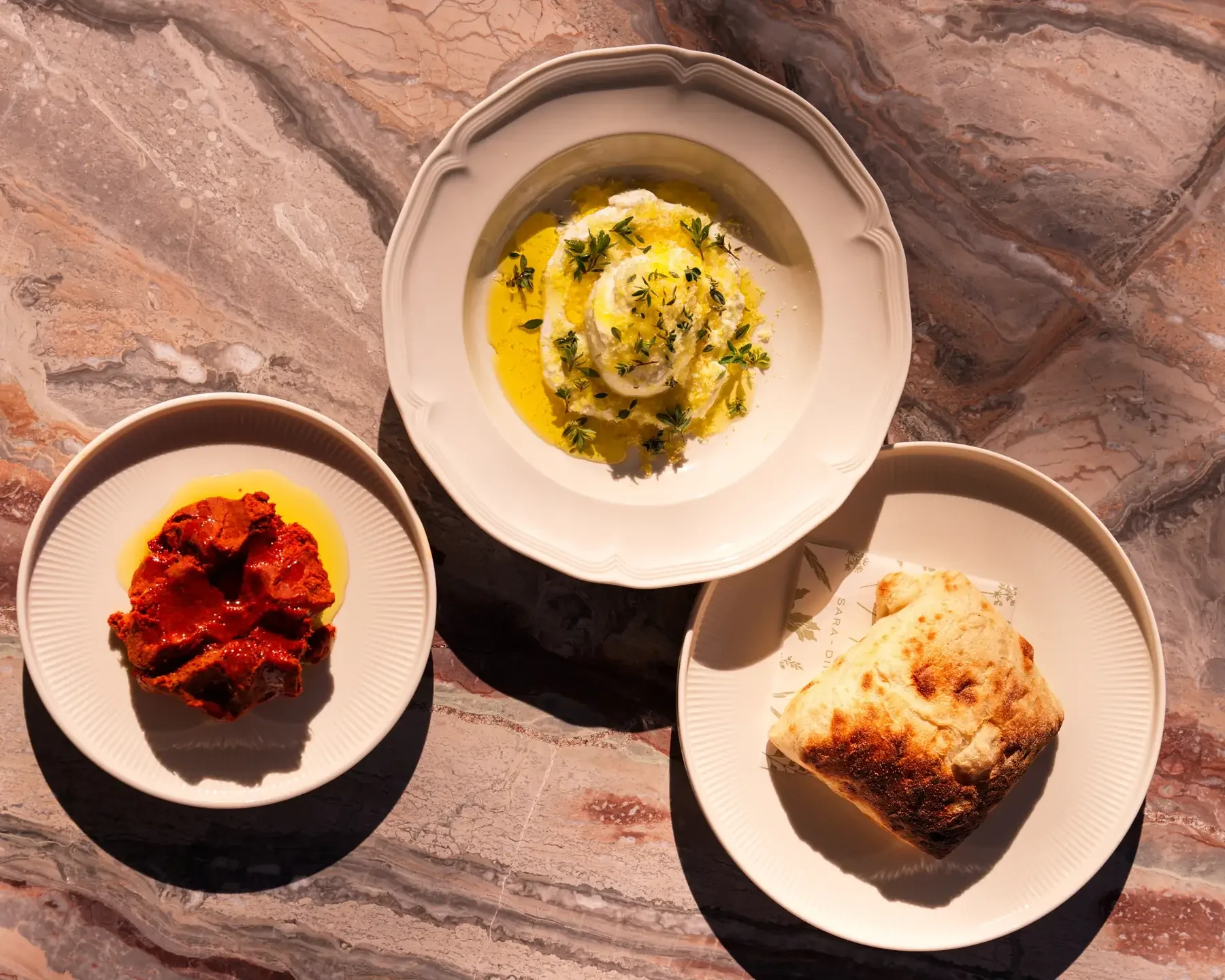 Burrata with olive oil and thyme, spicy nduja, and toasted focaccia on a marble table at Sara restaurant, Berry NSW