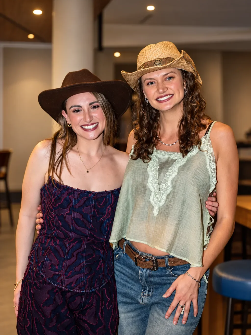 Two women pose together in cowboy hats at an Infynite Dating Events cowboy-themed party.