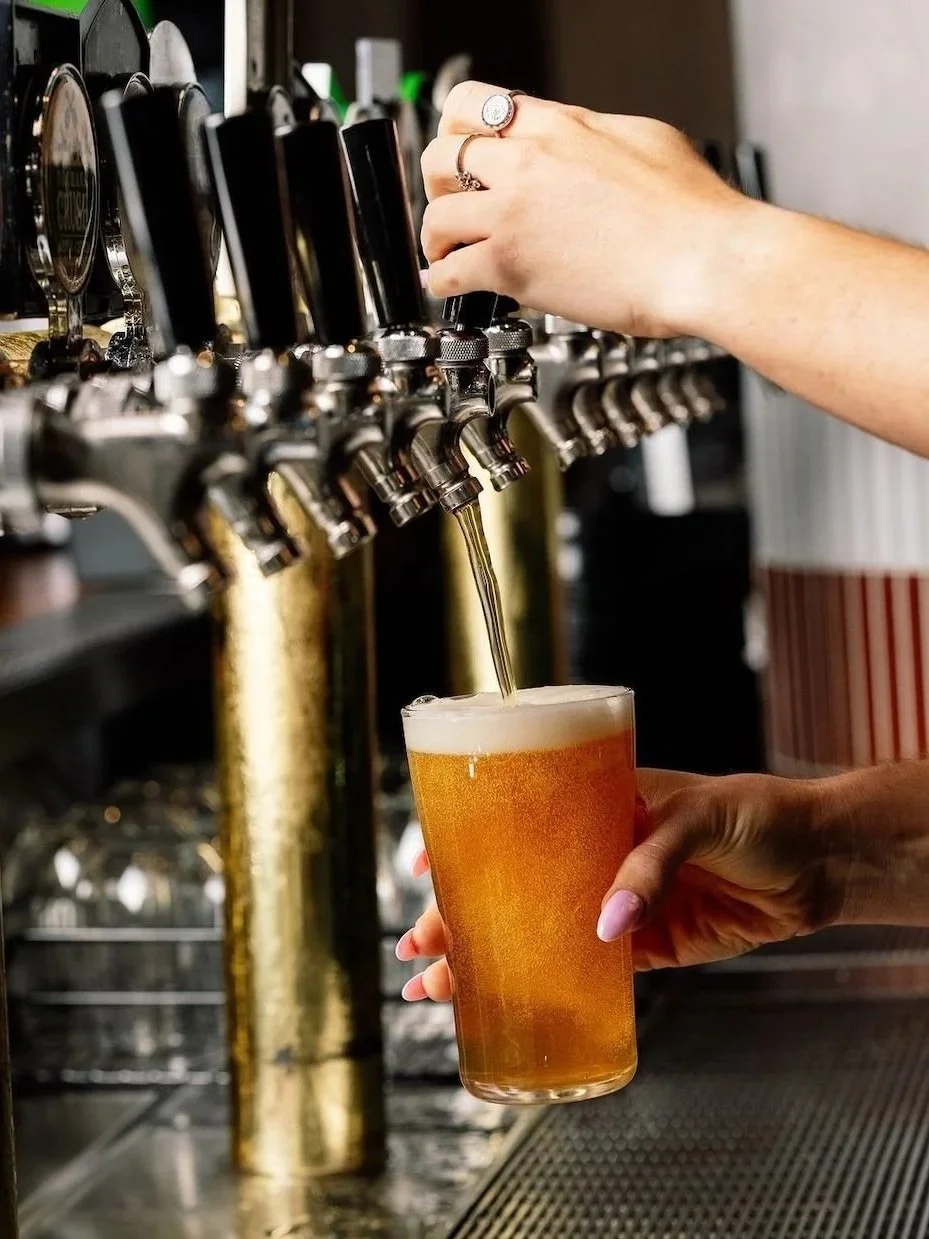 Bartender pouring a freshly tapped golden beer into a pint glass at Union Place Hotel in Jannali, featuring brass beer taps, a foamy head and a close-up of the bar service.