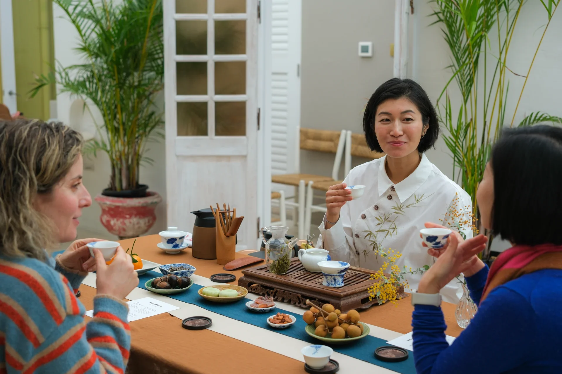 Chinese tea ceremony class with guests seated around a table, learning traditional tea preparation and tasting techniques.