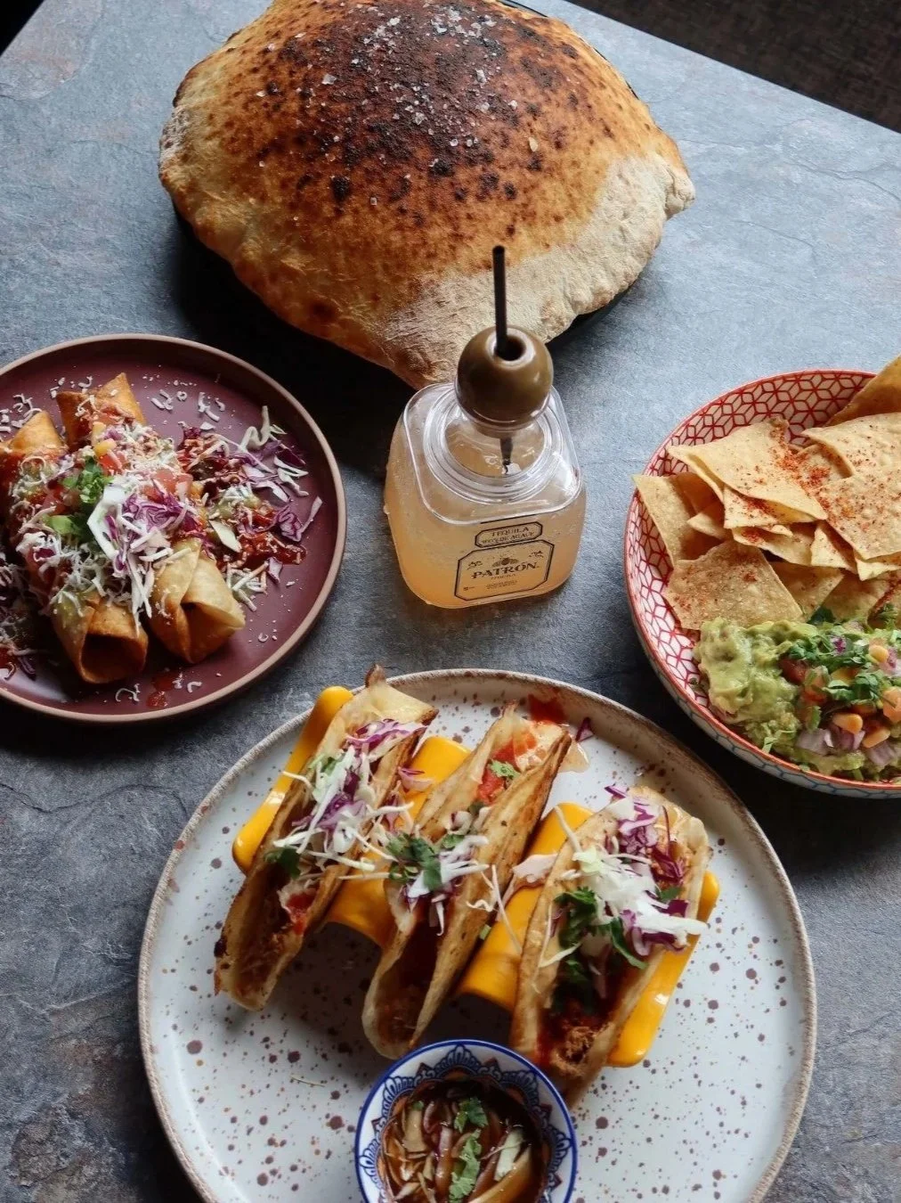 a selection of woodfired bread, tacos and tortilla chips with a bottle of tequila