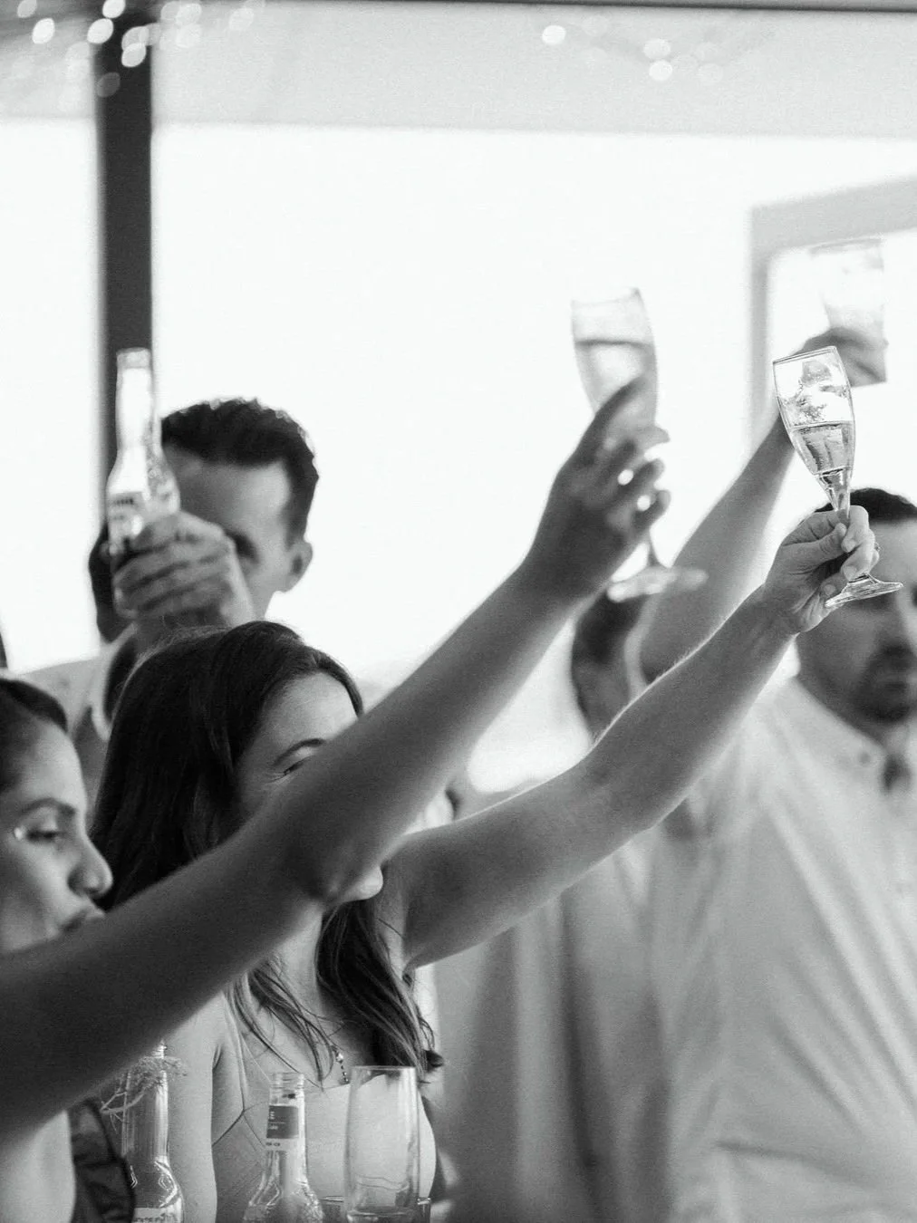 Black-and-white photograph of guests raising champagne glasses in a celebratory toast at The Founders Room at Wanda SLSC, capturing a lively social atmosphere.