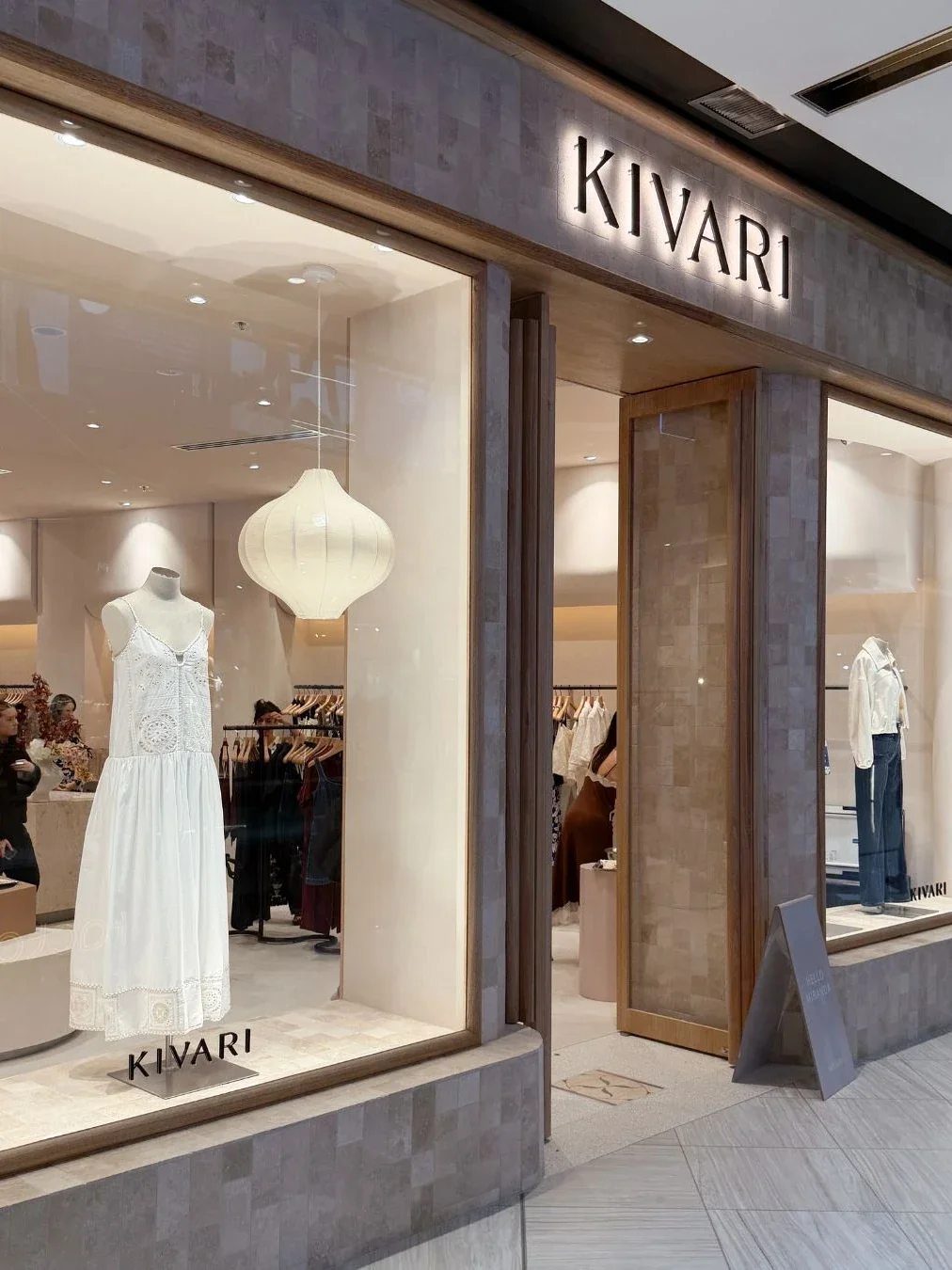The KIVARI storefront at Westfield Miranda, with a white broderie dress and cream lantern pendant light displayed in the window and a "Hello Miranda" sign near the entrance.