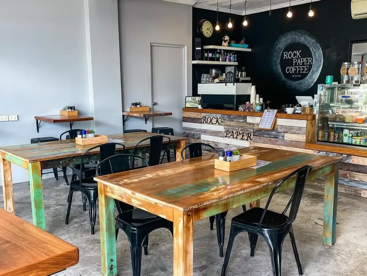 rock paper scissors cafe dining area featuring timber tables and bar, concrete floors and black metal chairs