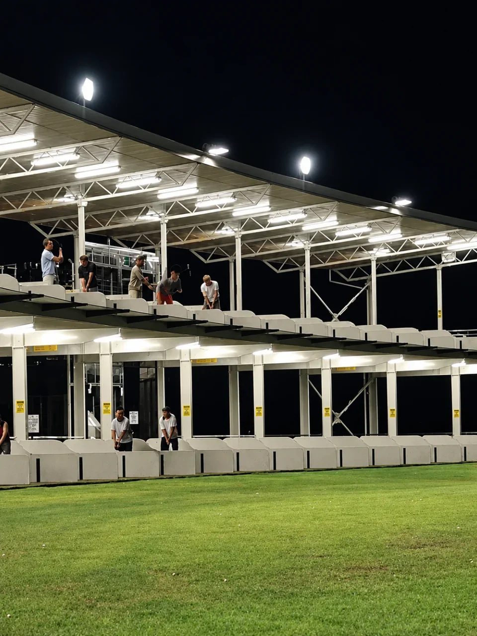 Golf driving range at The Ridge Sporting Complex, Barden Ridge, lit up at night.