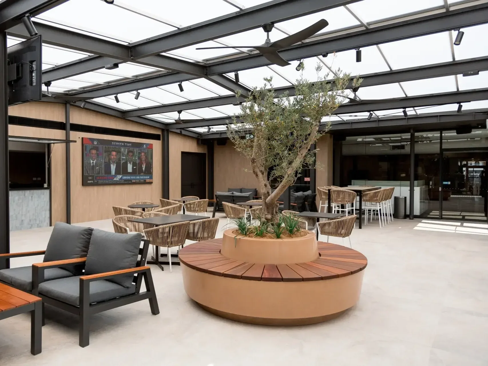 an undercover modern outdoor dining area with a central olive tree