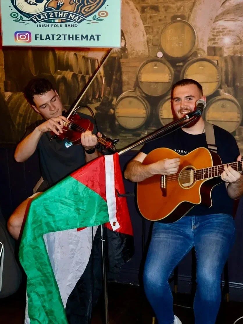 two musicians with a violin and guitar performing at snug bar