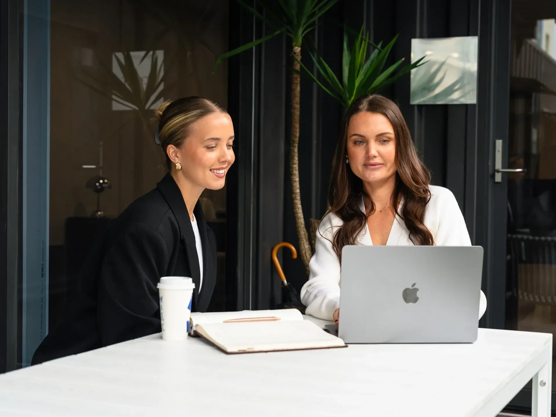 Two people discussing home loan options with a mortgage broker while looking at a laptop.