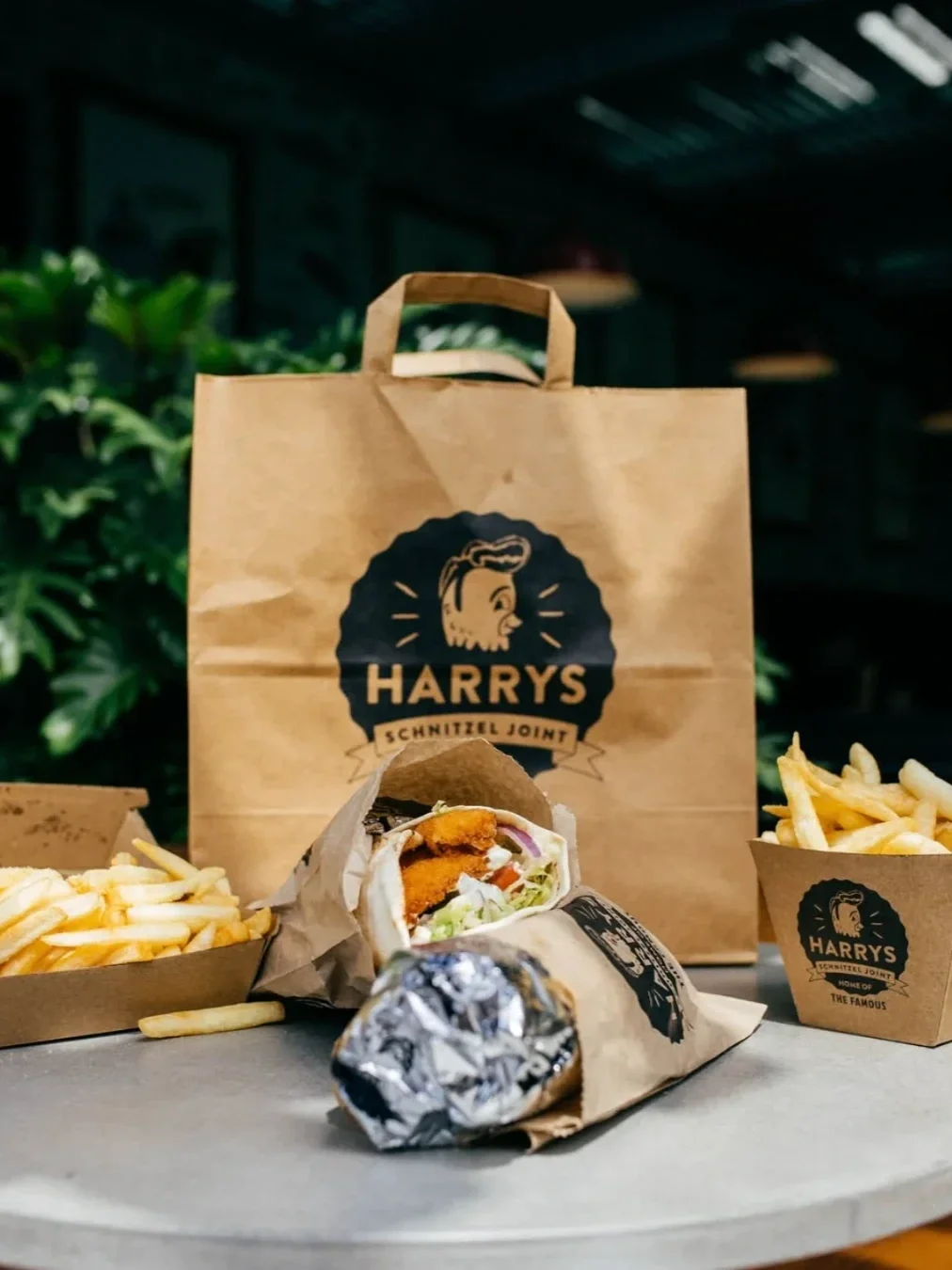 Takeaway spread from Harry’s Schnitzel Joint featuring schnitzel wraps, hot chips and branded packaging.