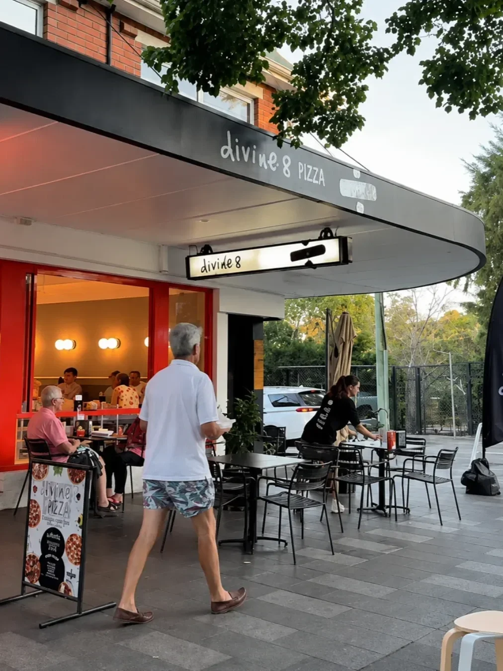 Exterior of Divide 8 Pizza in Gymea, with customers dining at outdoor tables beneath the shopfront awning.