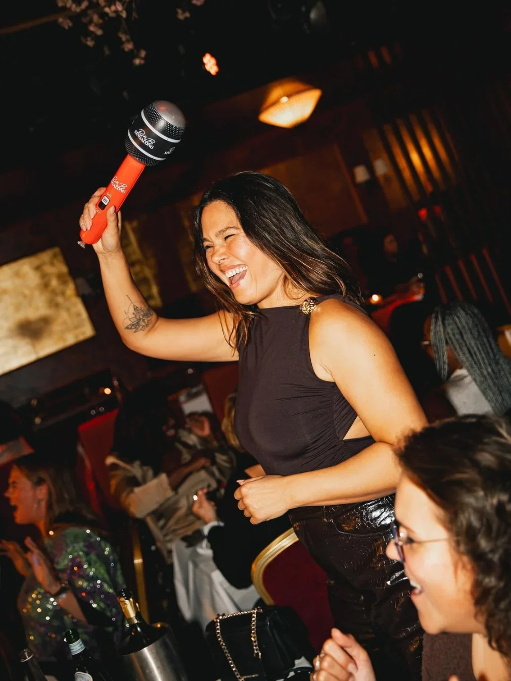 A woman laughs and holds up an inflatable microphone at a comedy night at Cronulla RSL.