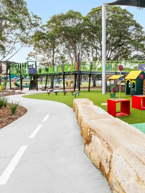 Colourful children’s playground at Cooper Street Reserve in Engadine, featuring climbing equipment, playhouses and a winding bike path.