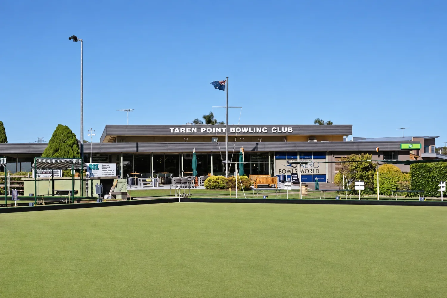 Taren Point Bowling Club clubhouse seen across the bowling green, with an Australian flag flying out front.
