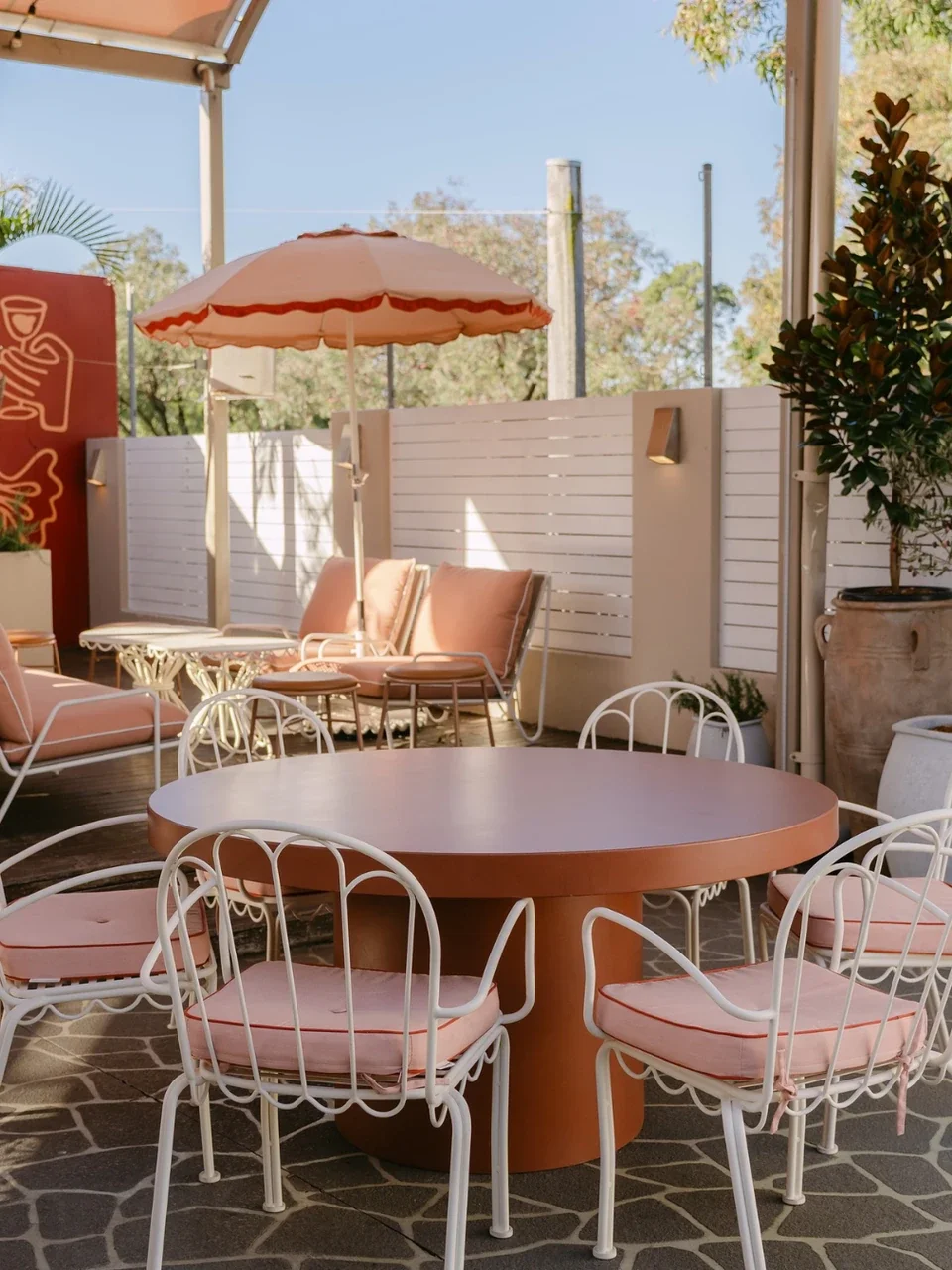 Outdoor terrace dining area at Bangor Tavern, Bangor, with a round table, cushioned chairs and a striped umbrella.
