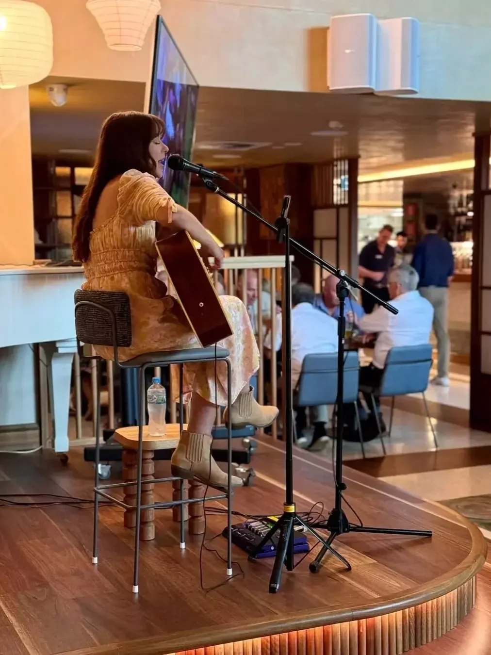a woman playing guitar and singing at folk at tradies gymea