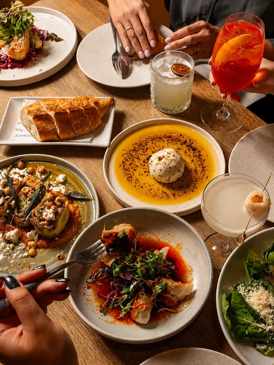 A table of shared dishes, bread and cocktails at Rocksalt, Menai.