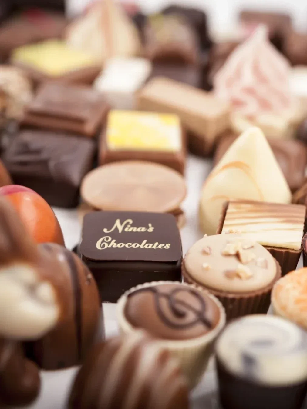 Close-up assortment of handmade chocolates from Nina’s Chocolates, featuring a mix of milk, dark and white chocolate varieties.