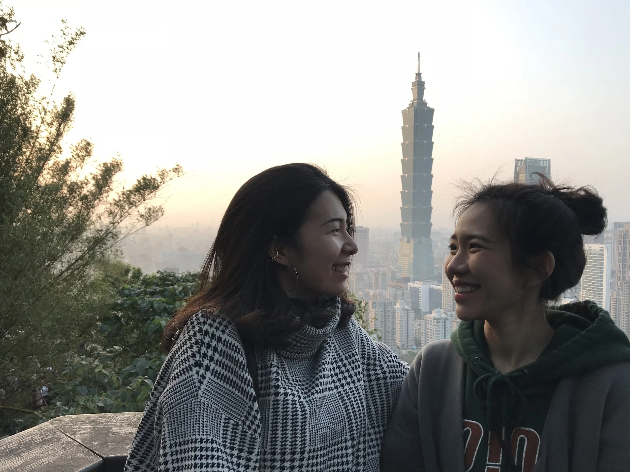 Ashley Chang and a friend posing for a picture in front of the Taipei 101 tower.
