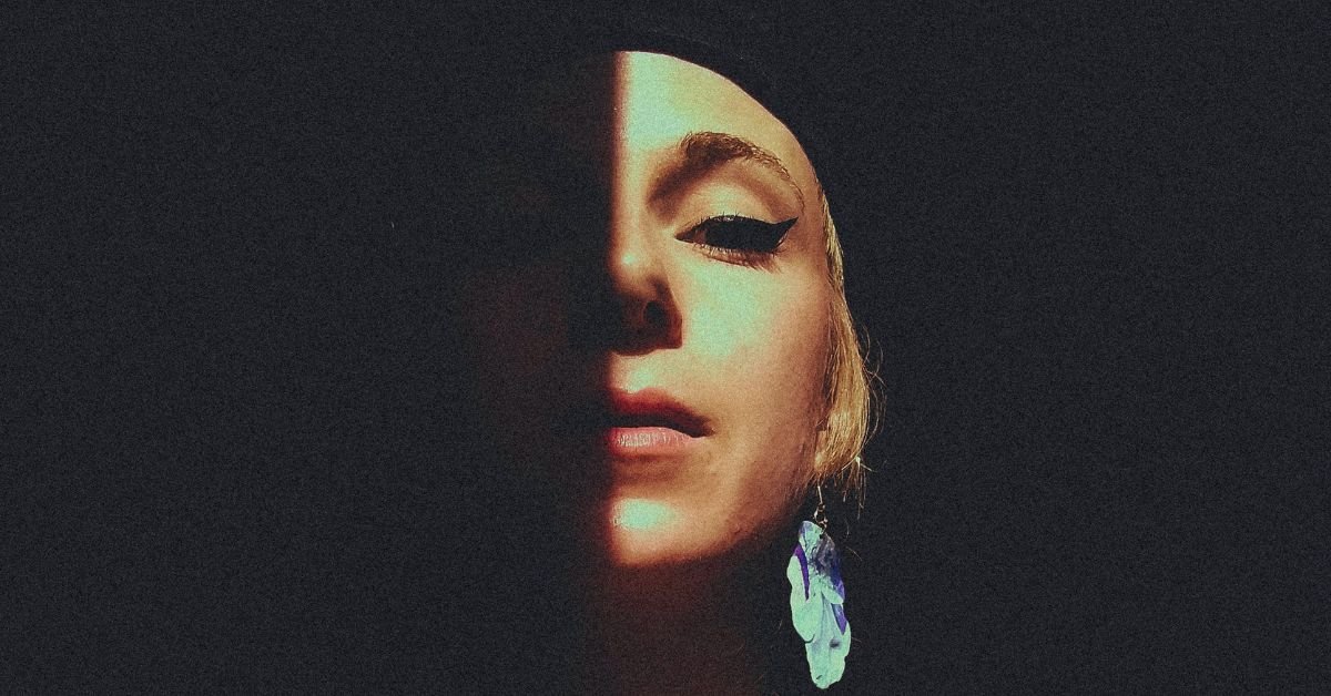 A woman staring at the camera with half her face in shadow