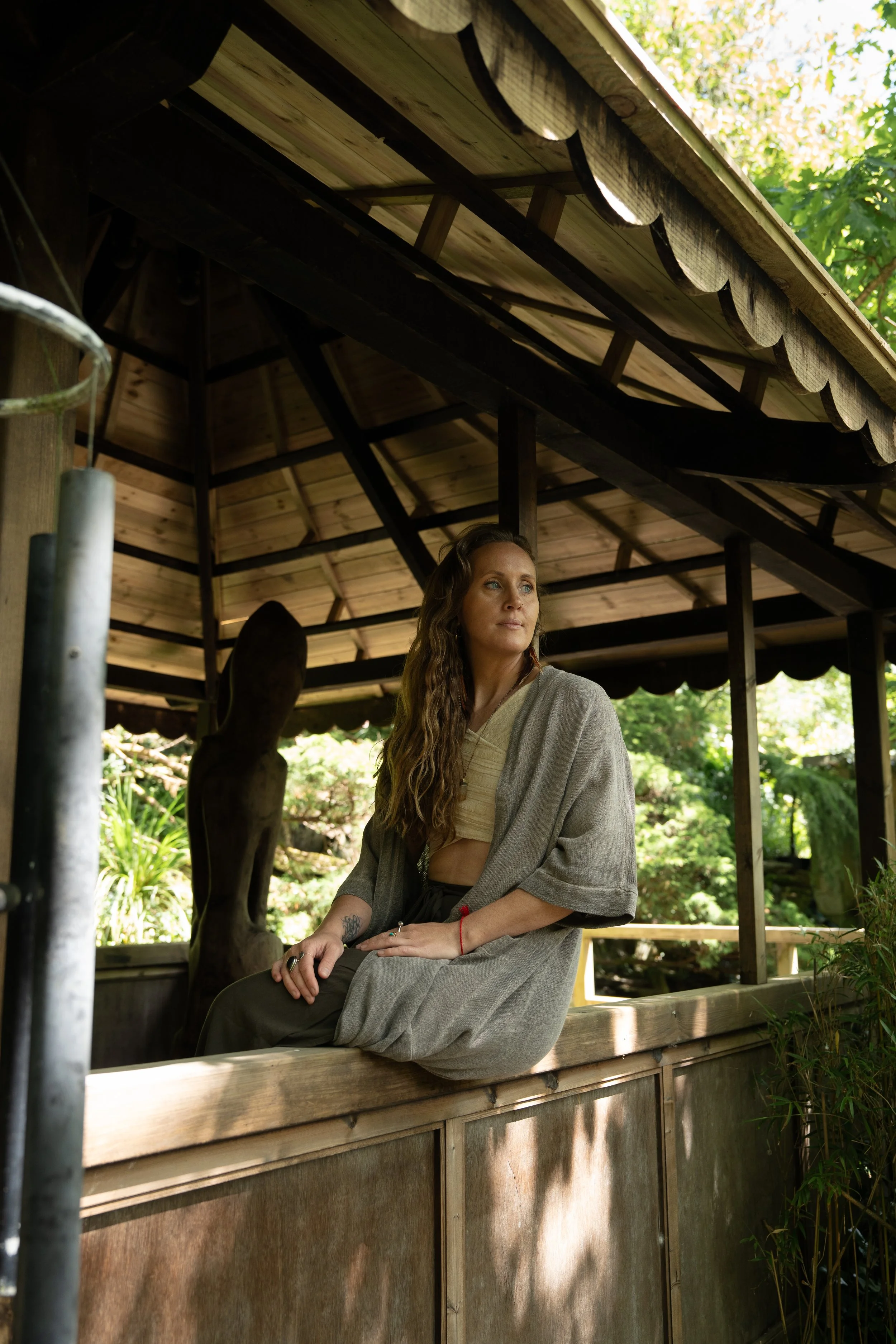 Woman practicing yoga or meditation seated on a fur-lined mat with candles, a singing bowl, and plants nearby in a calm, minimalist room.