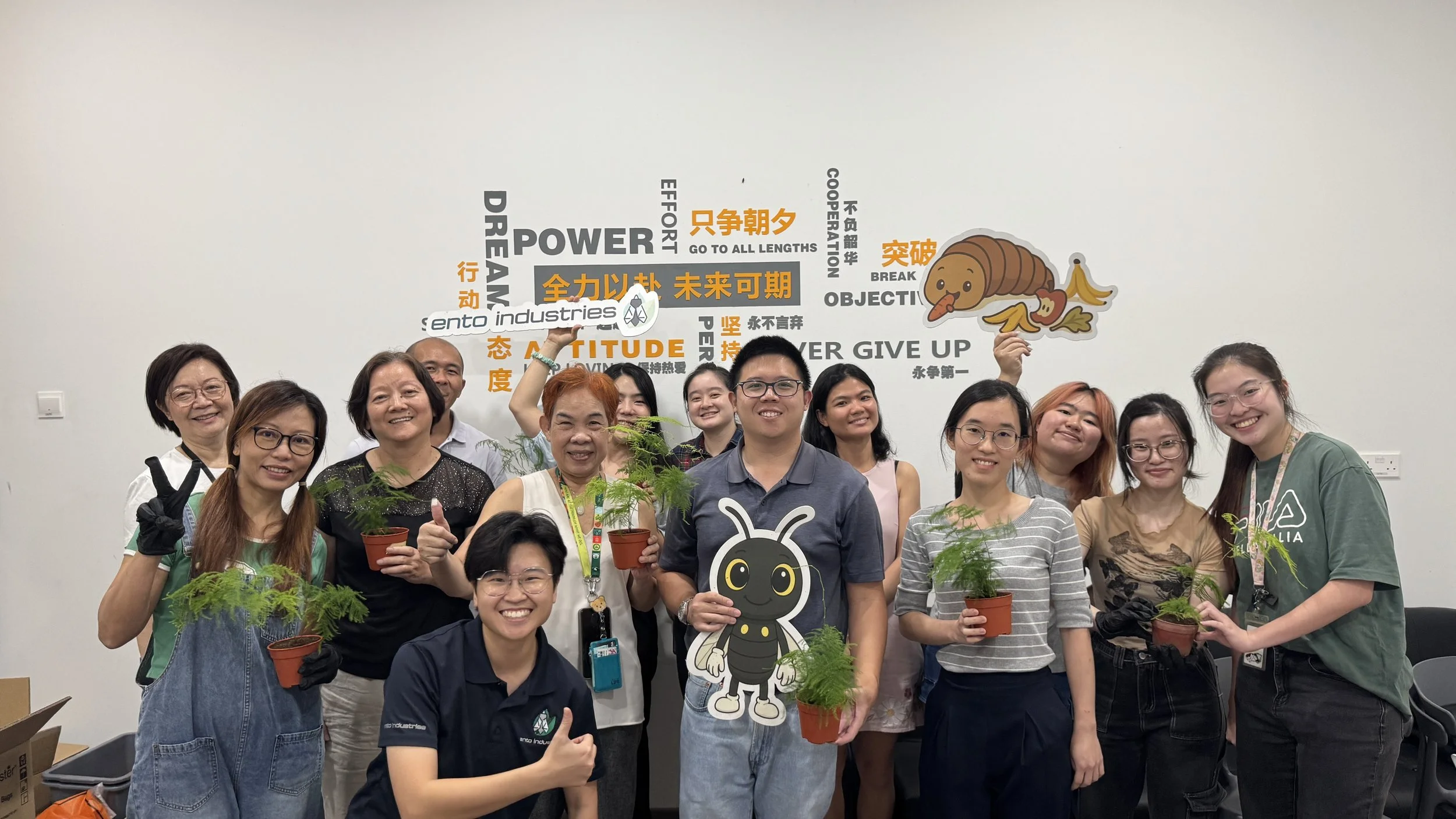 A group of diverse smiling and posing with their very own repotted asparagus fern done at Ento Industries. The repotting is done with Ento Industries' Organic Black Soldier Fly Frass