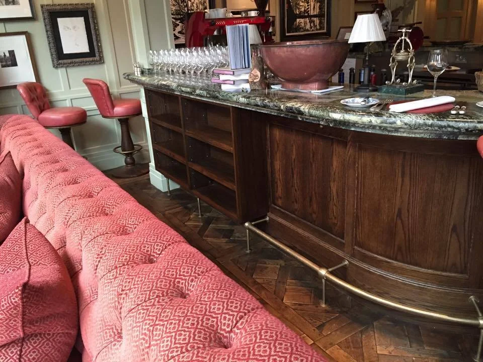 Living room with a salmon pink upholstered sofa and bar area featuring a granite countertop, wine glasses, and decorative items.